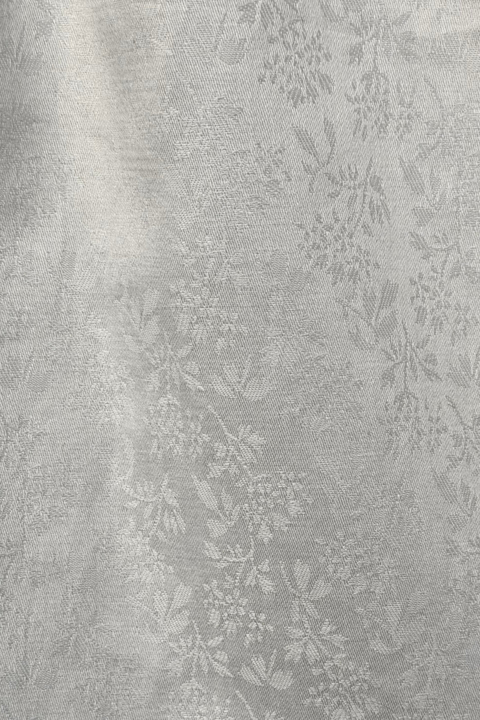 Close up of a white textured cotton skirt with subtle floral pattern