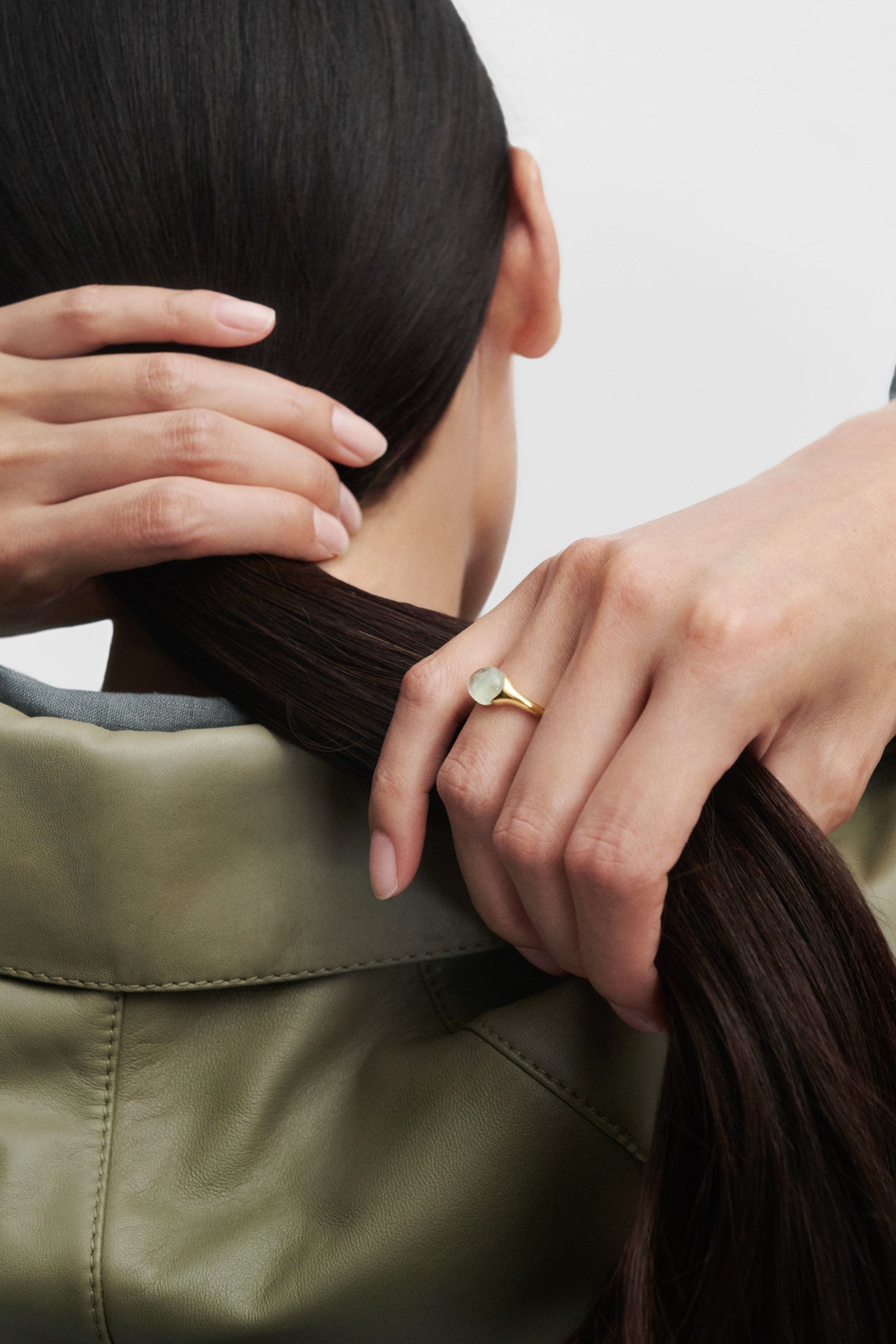 Person wearing a gold ring with a plain background