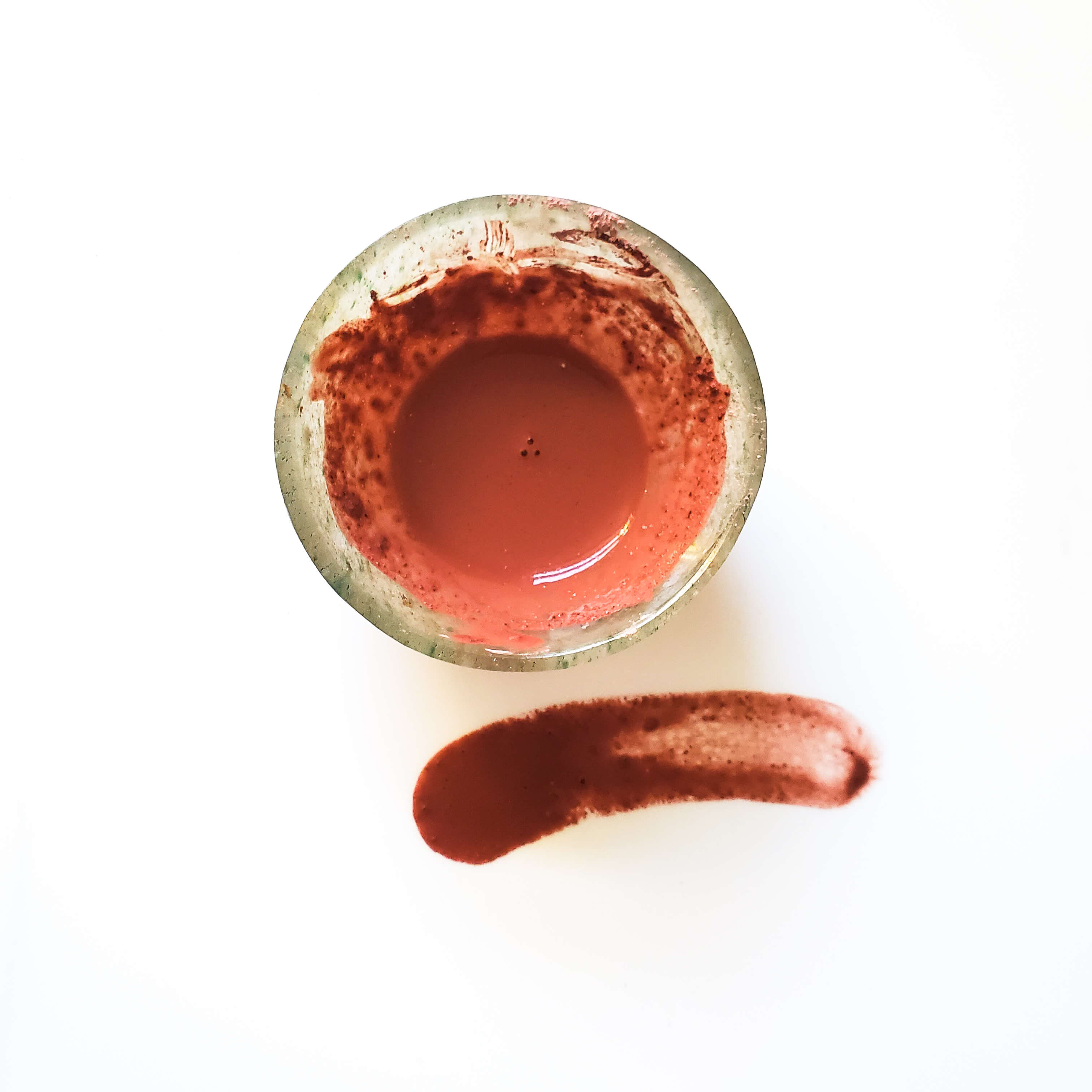 clay mask mixed in a small bowl with a swatch on a white background