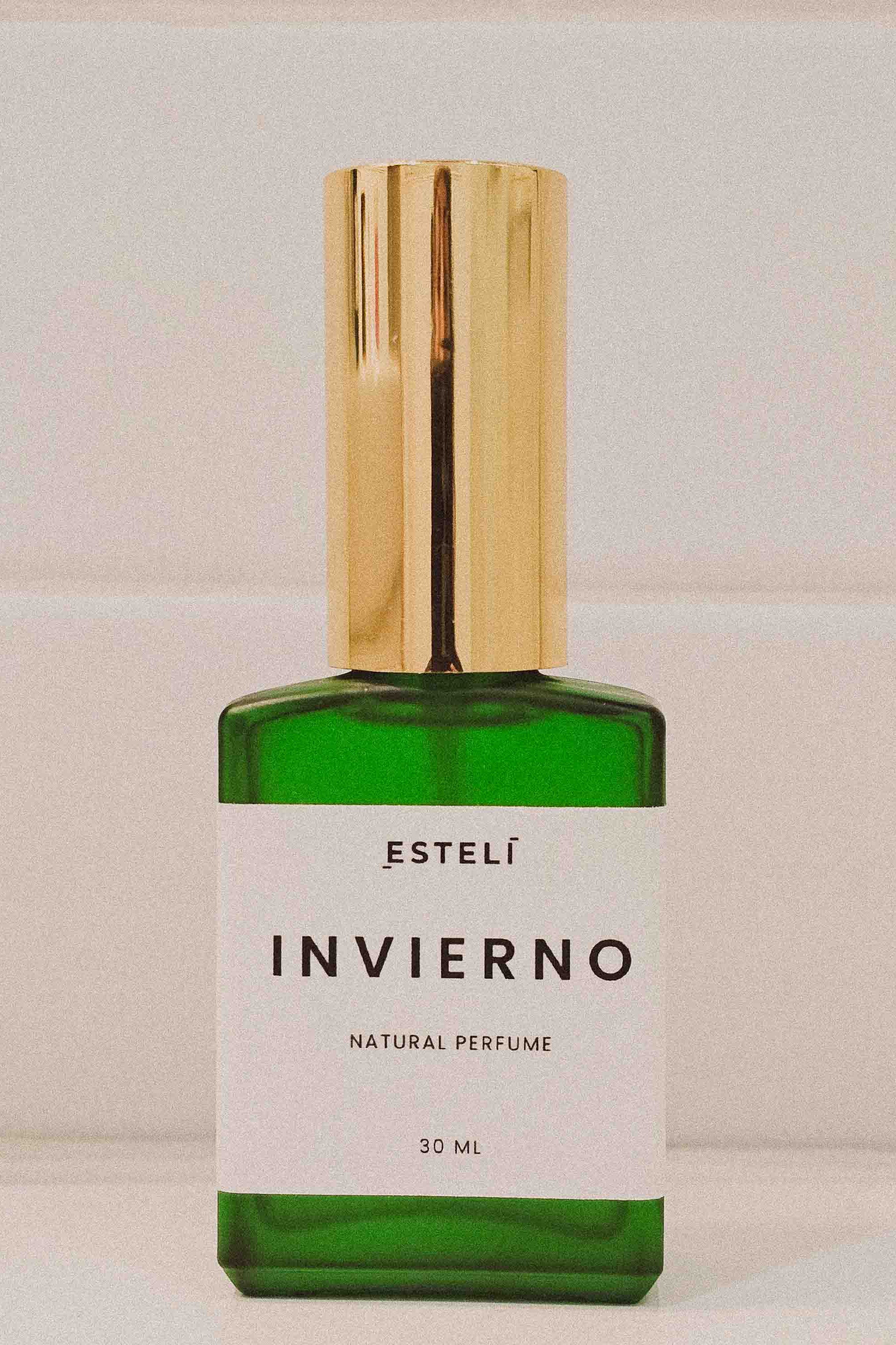 Green perfume bottle with gold cap labeled 'Estelí Invierno' on a light background
