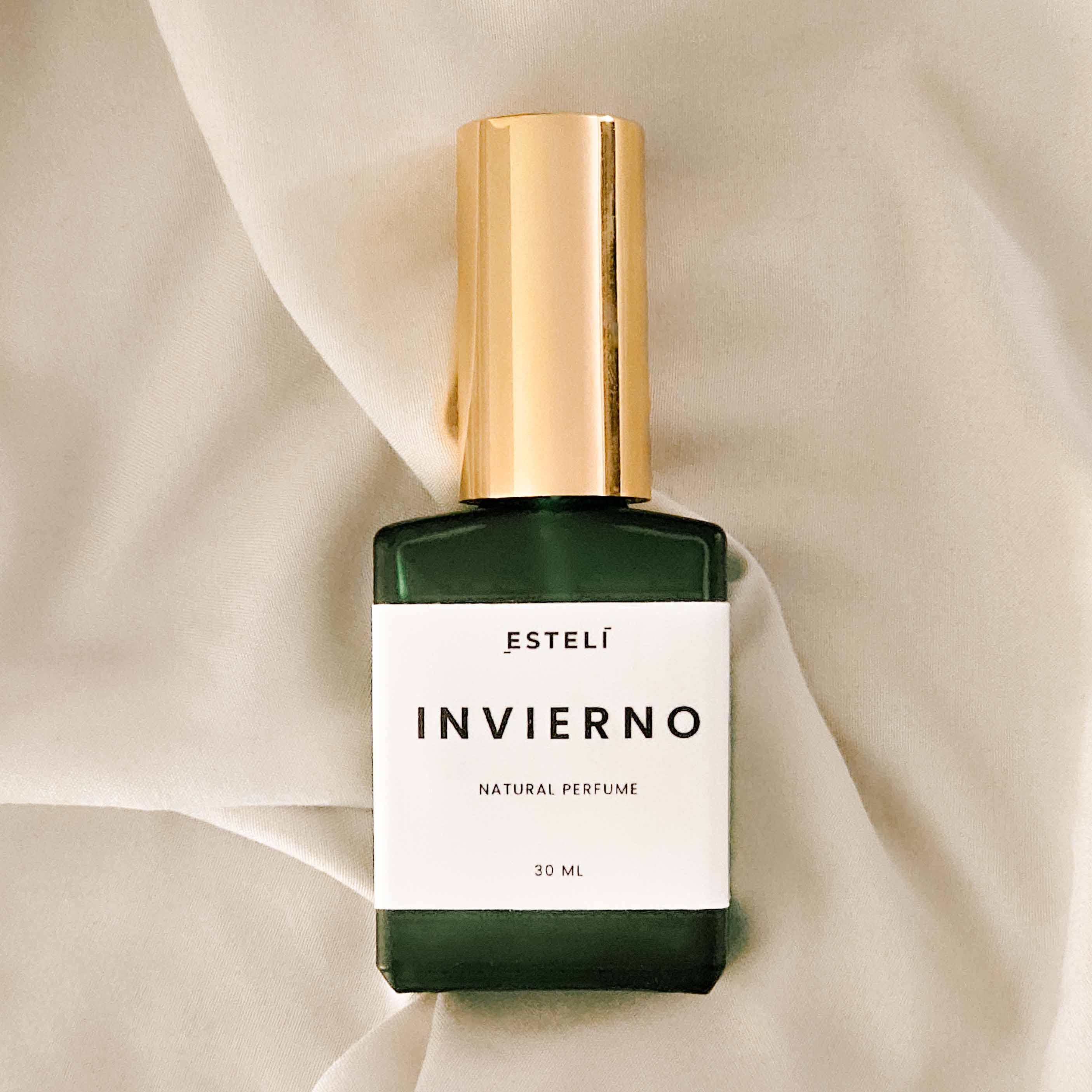 Perfume bottle labeled 'Estelé Invierno' on a beige fabric background