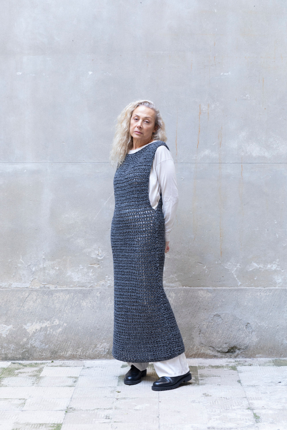 Person wearing a long textured wool dress against a gray wall