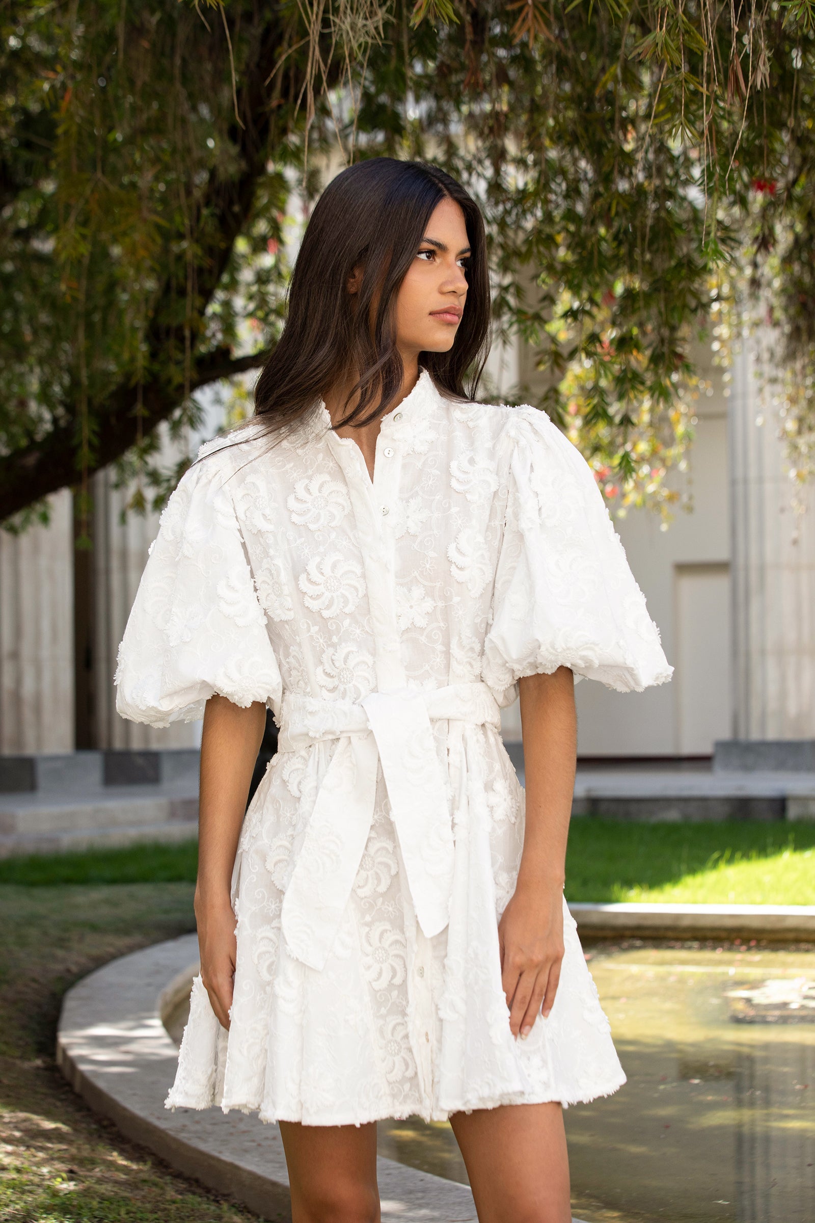 Woman wearing a white dress with puffed sleeves in an outdoor setting