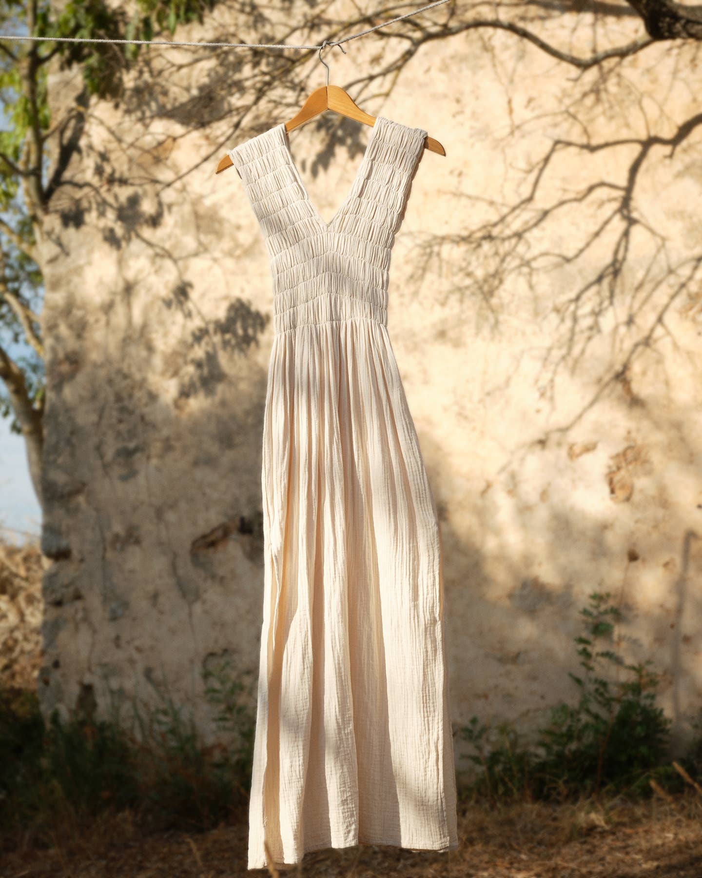 Long dress hanging on a hanger against a textured wall with natural light