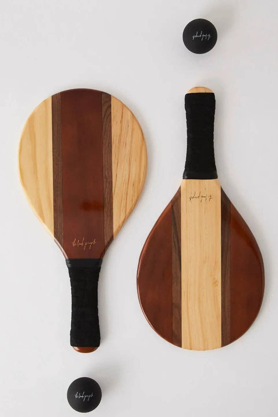 Two wooden paddle sports with black handles on a white background