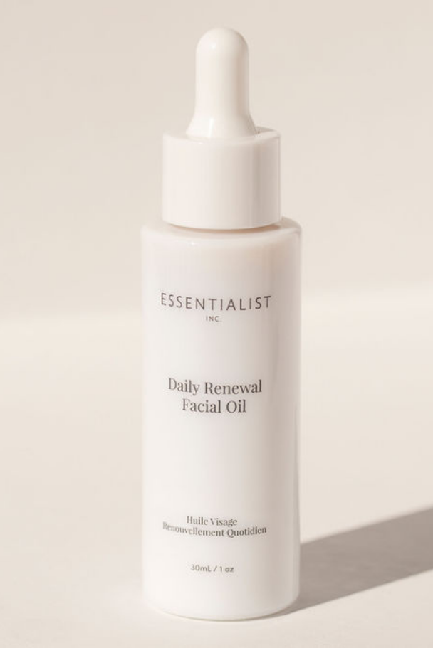 White bottle of Essentialist Daily Renewal Facial Oil on a light beige background