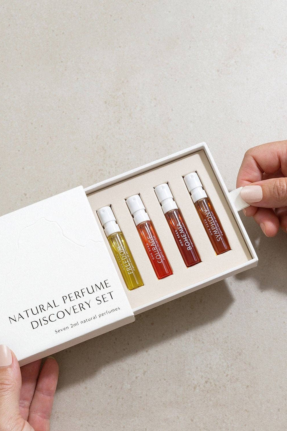 Small perfume bottles in a 'Natural Perfume Discovery Set' box on a neutral background