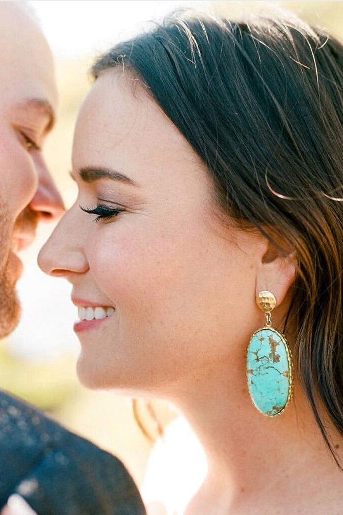 Woman wearing turquoise earrings with a blurred background