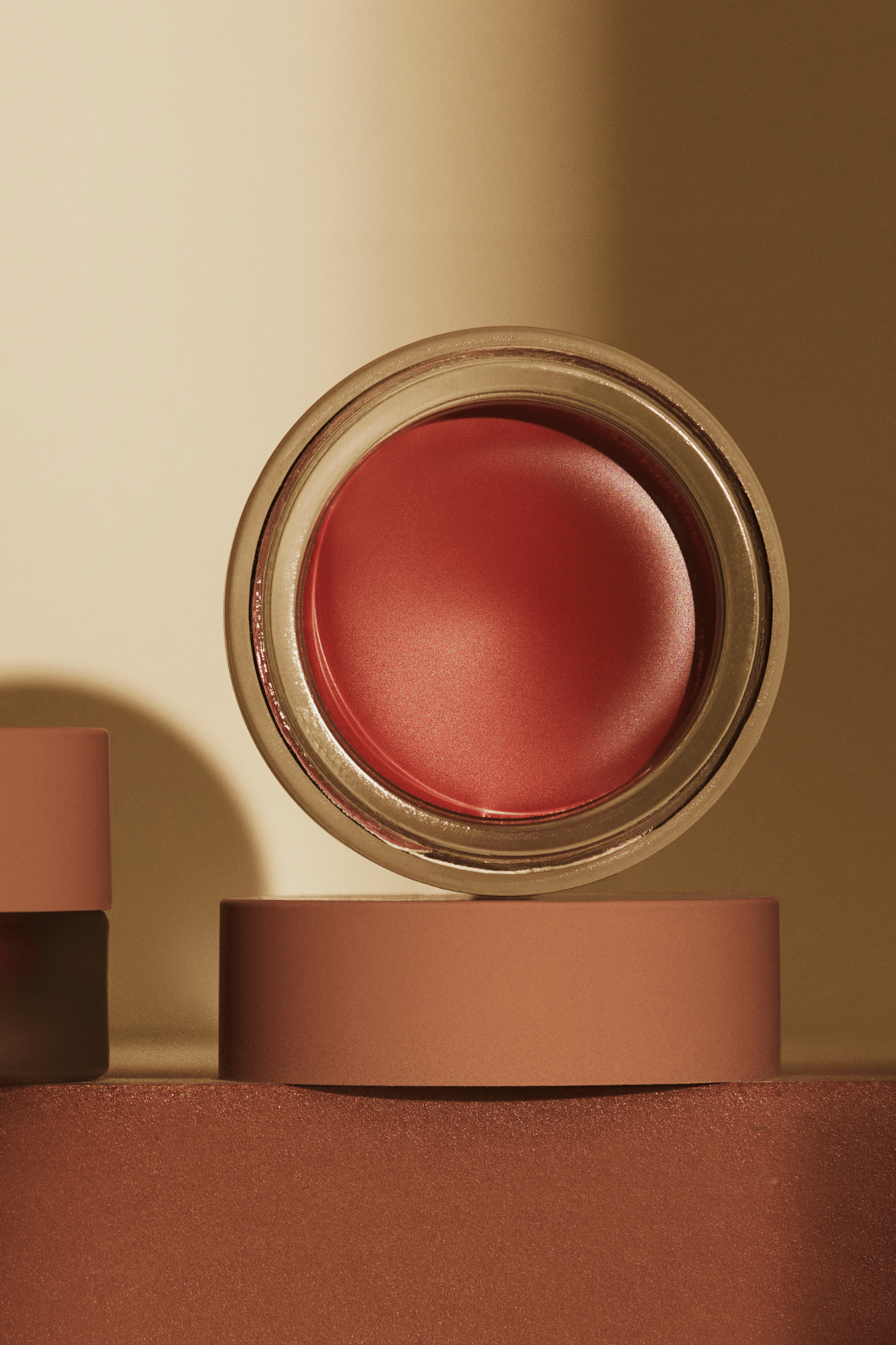 A close-up image of a scarlet cream blush, showing the product's texture and color.