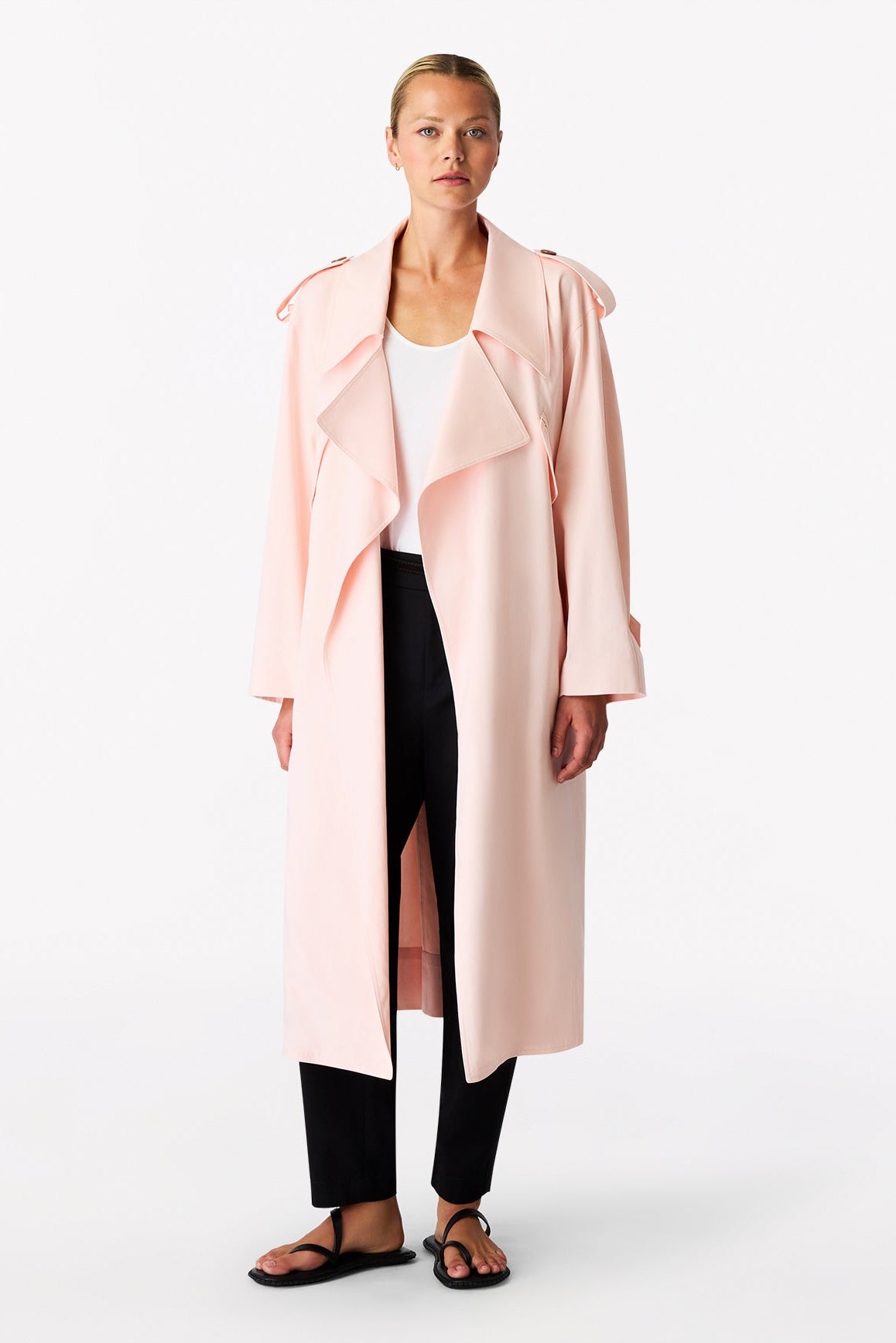 Woman wearing a long light pink coat on a white background