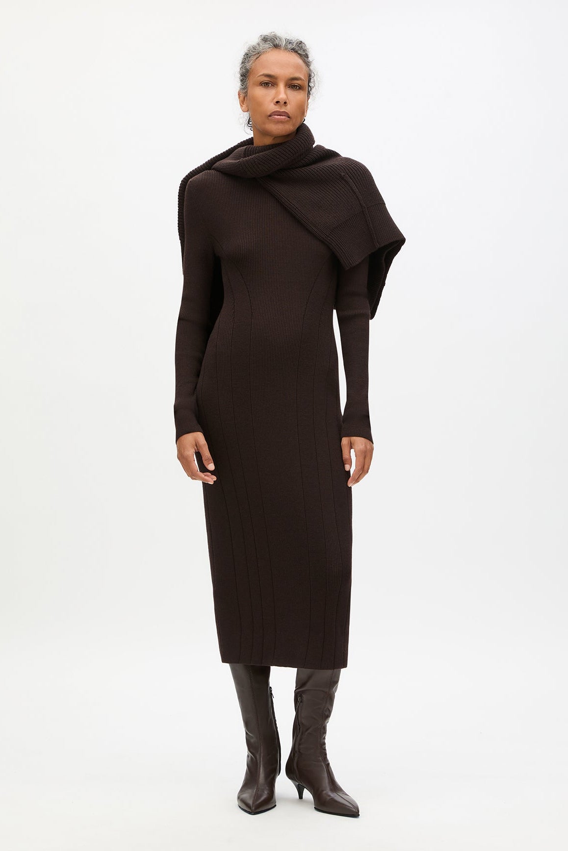 Woman wearing a dark brown dress with a draped design on a white background