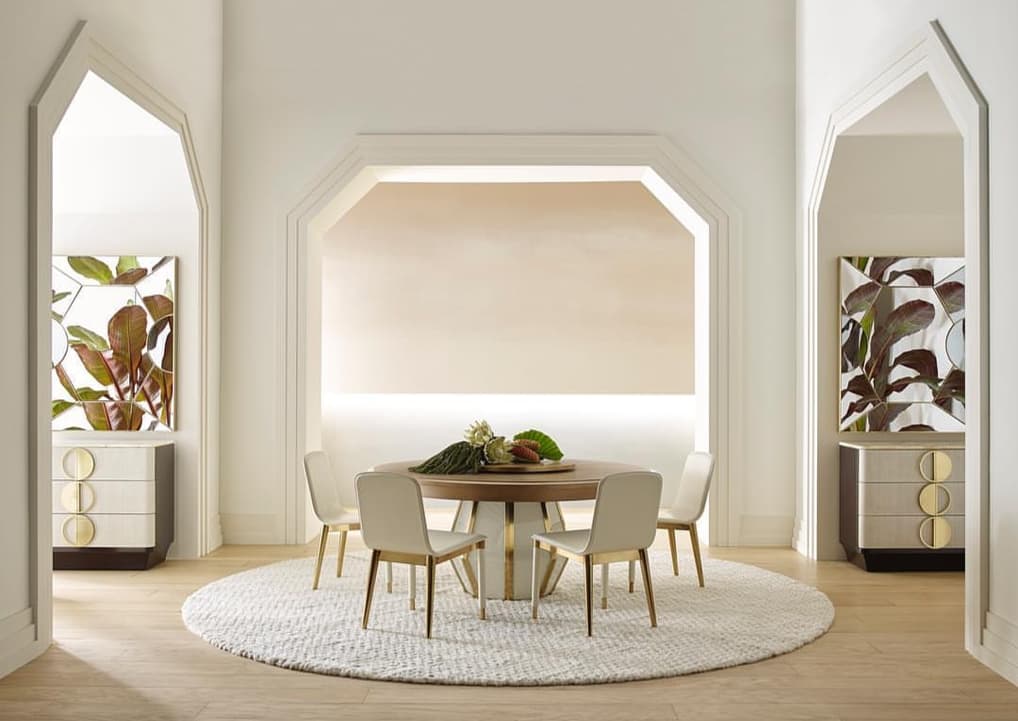 Modern dining room with a round table and chairs over round ivory wool rug in a stylishly decorated room.