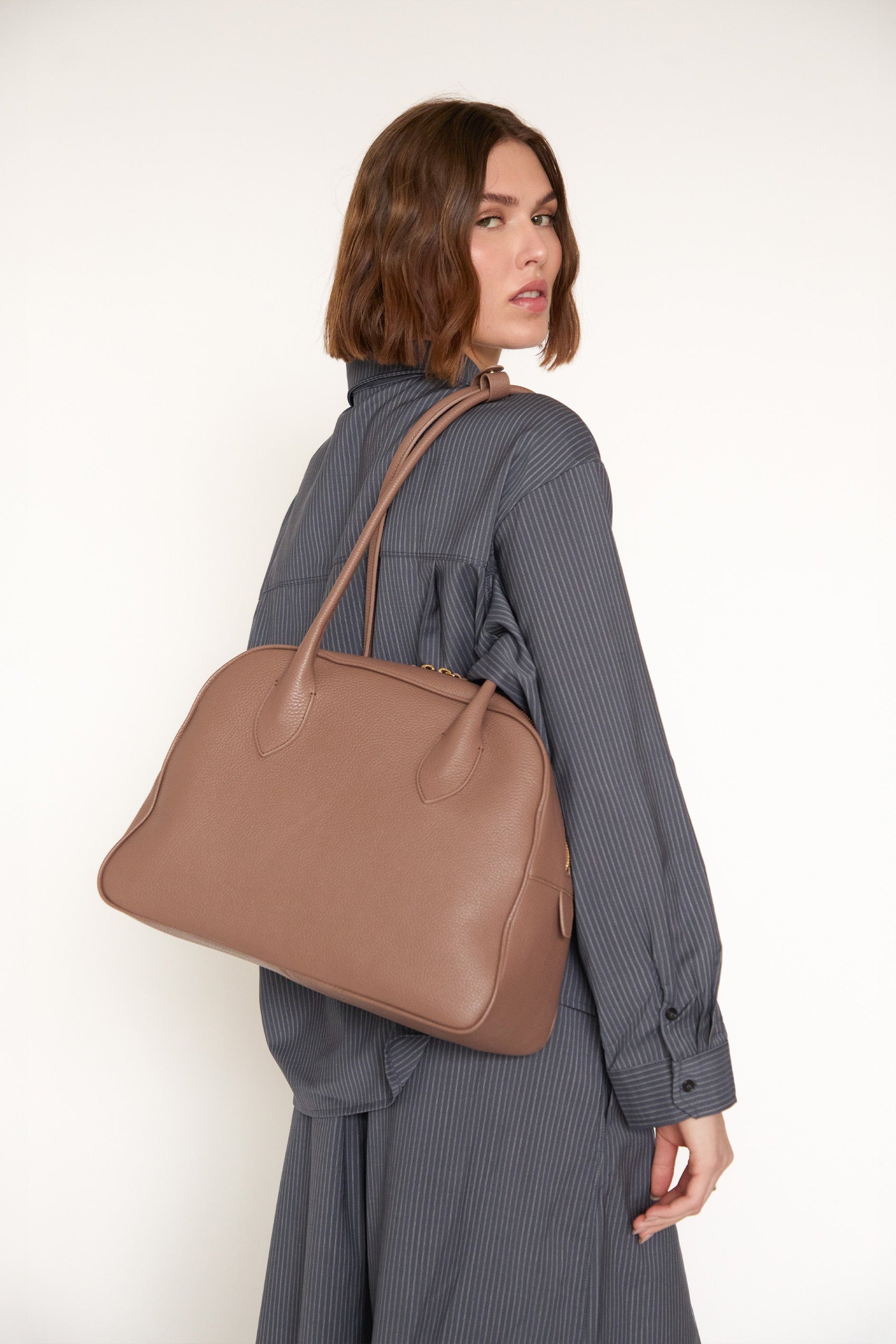 Woman carrying a brown handbag on a white background