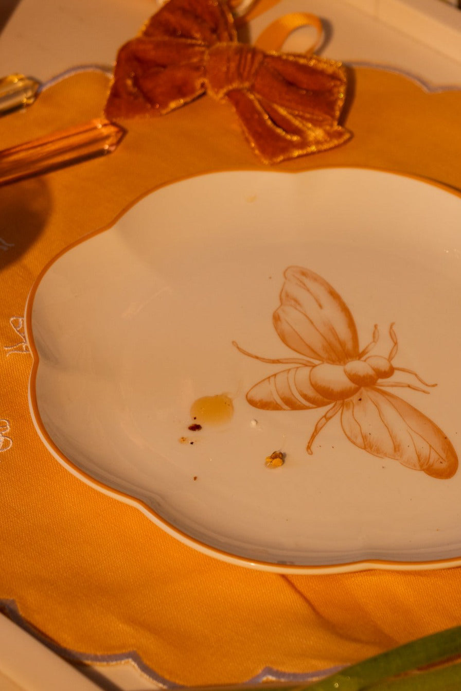 bee motif dinner plate on a decorative placemat with a candle in the background