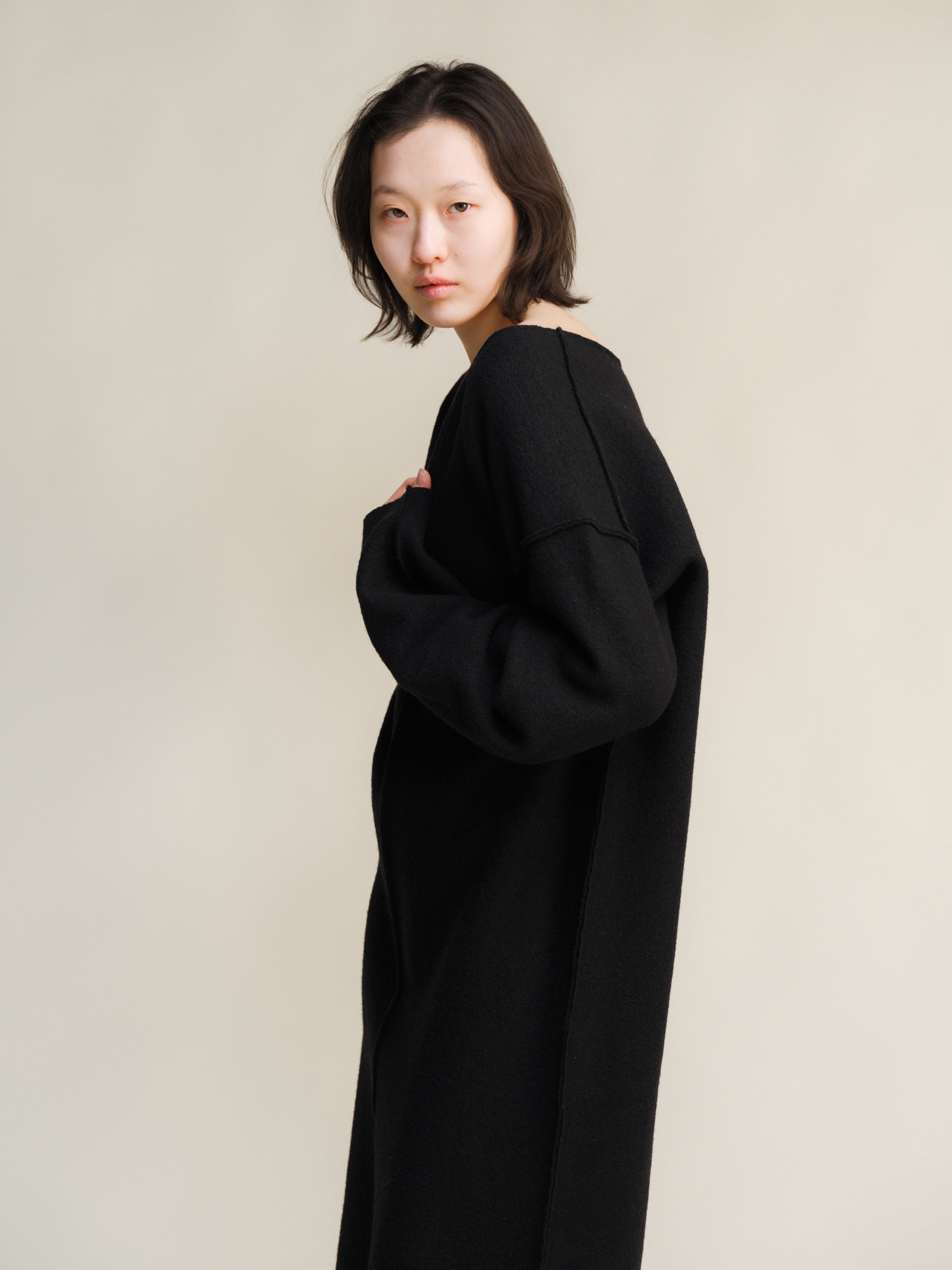 Person wearing a black dress against a plain background