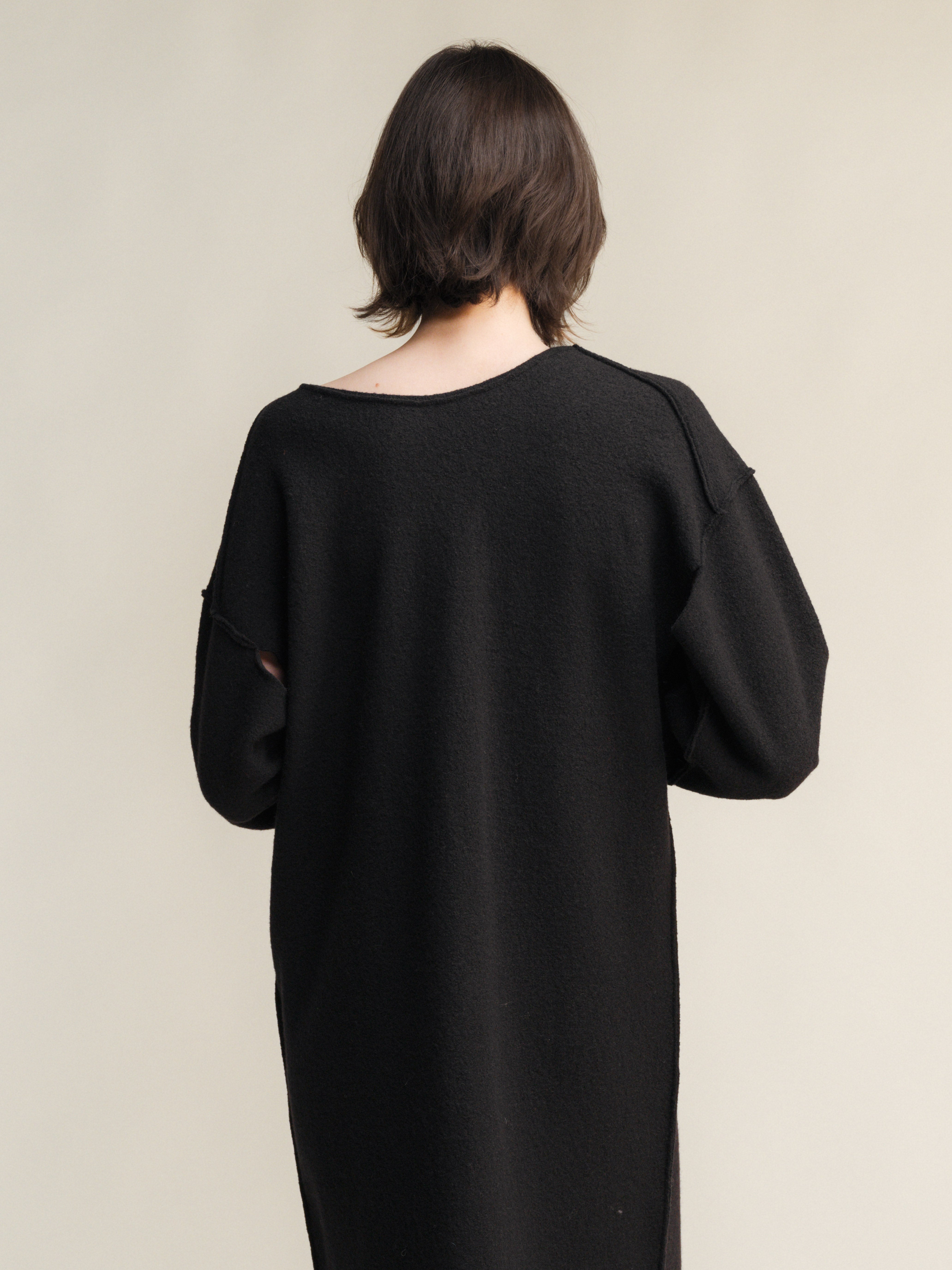 Person wearing a black dress with puffed sleeves against a beige background