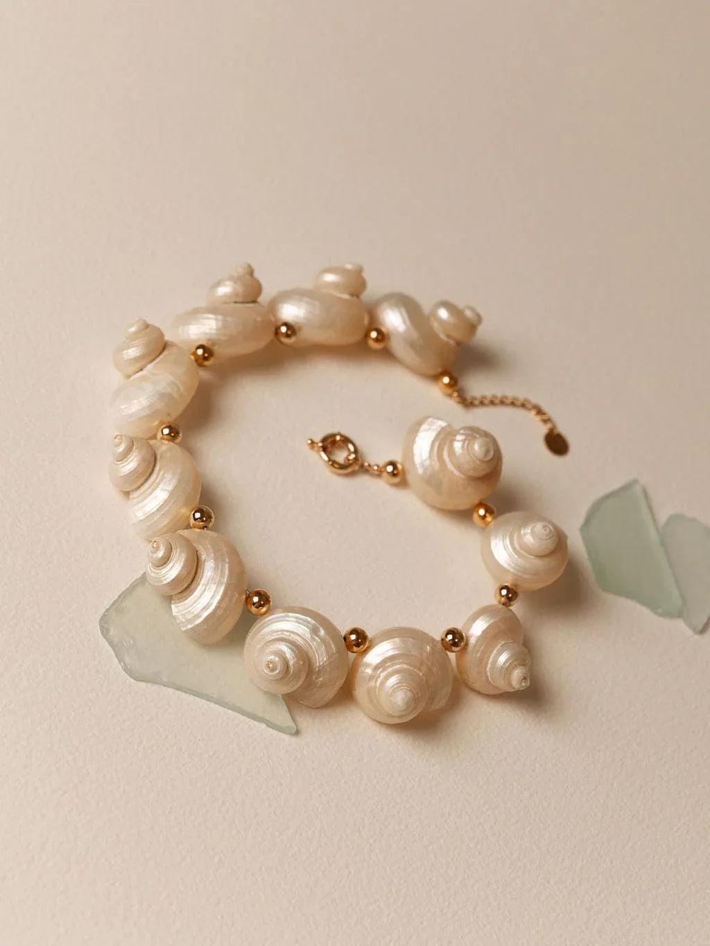 Seashell bracelet with gold accents on a light beige background