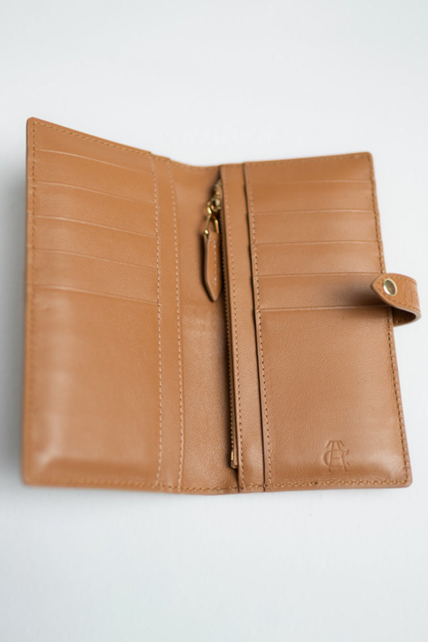 A tan leather wallet shown open against a light gray background, featuring card slots, a central zip pocket, and a small embossed logo on the lower right.