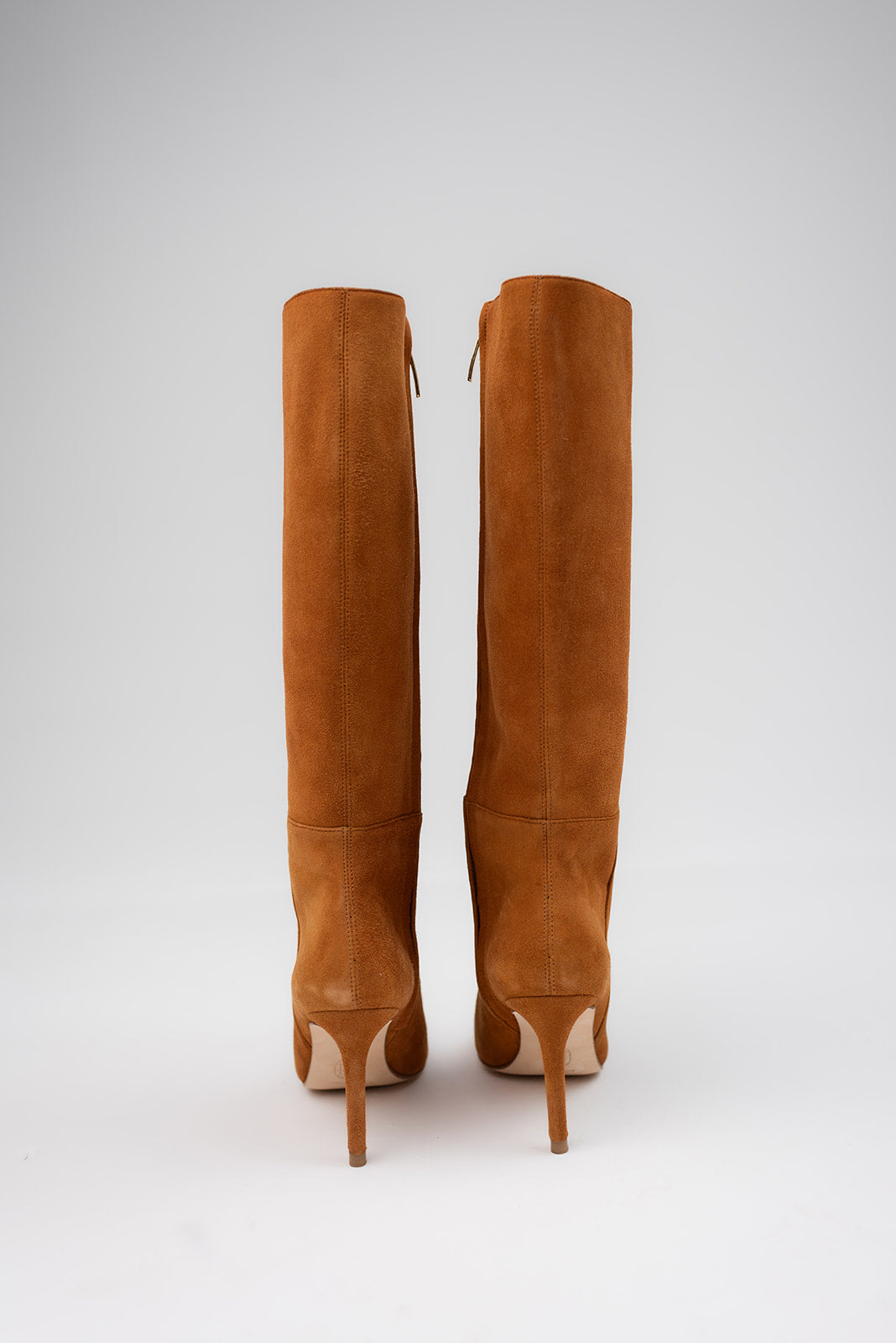 A pair of tall brown suede knee-high boots with stiletto heels, shown from the back against a light gray studio background.