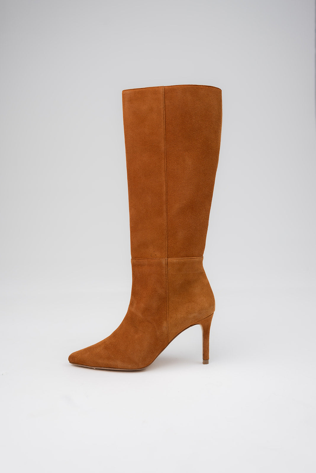 A single knee-high pointed-toe stiletto boot in tan suede, shown in profile against a light gray studio background.