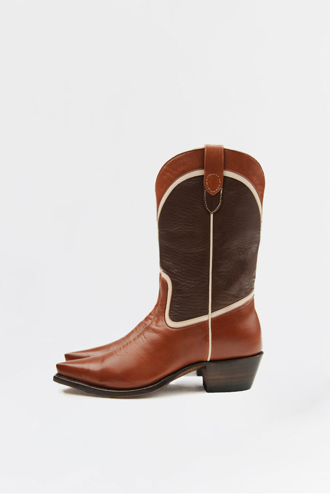 A single brown leather cowboy boot with a dark brown shaft panel, cream-colored stitching, and a dark stacked heel, shown from a side profile on a light gray background.