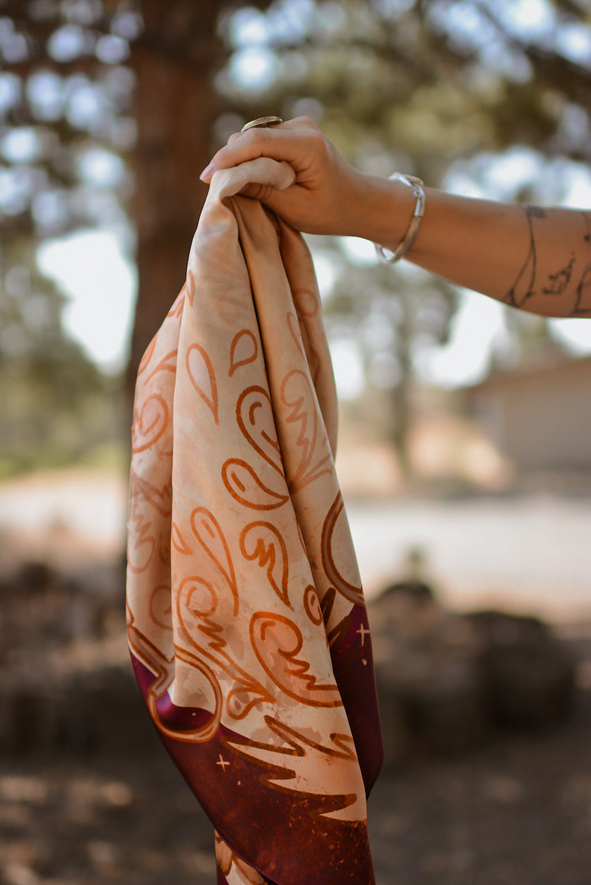 Person holding a patterned fabric in a natural setting with trees and blurred background