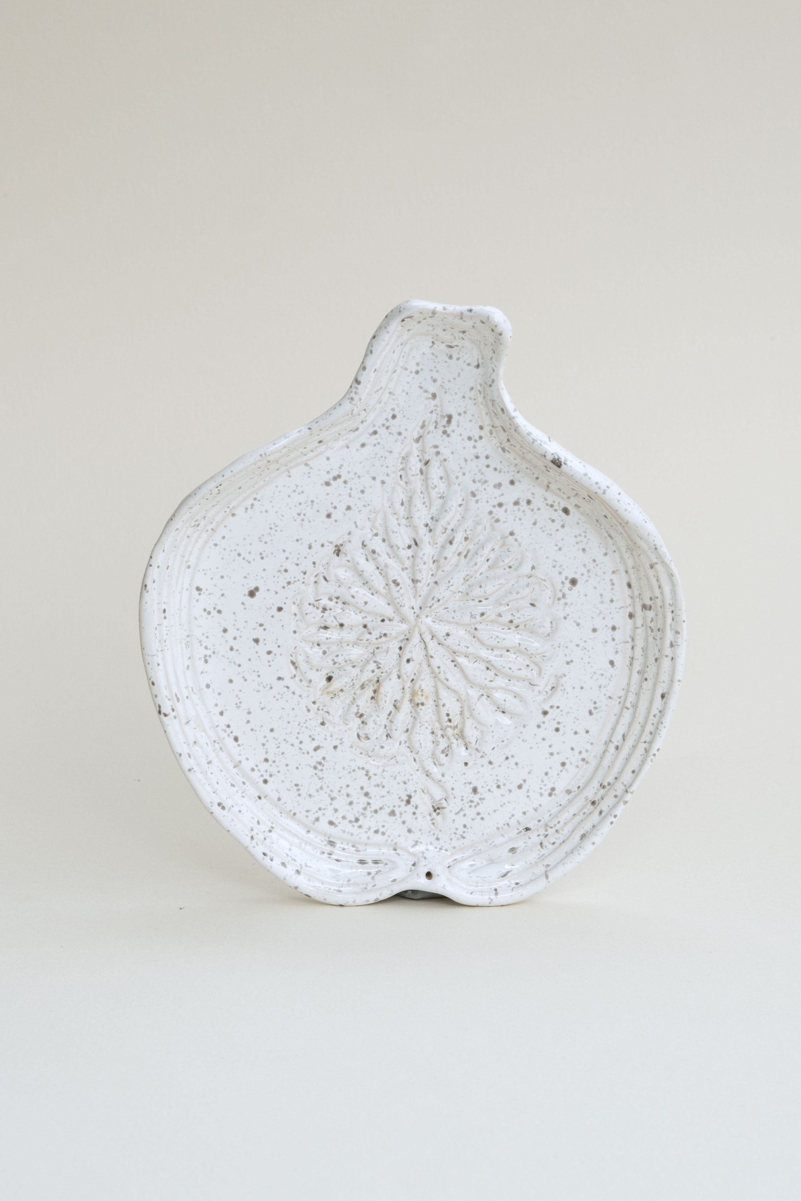 Speckled ceramic dish on a light beige background