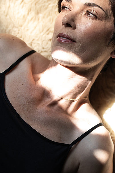 Woman lying on a textured surface with sunlight casting shadows