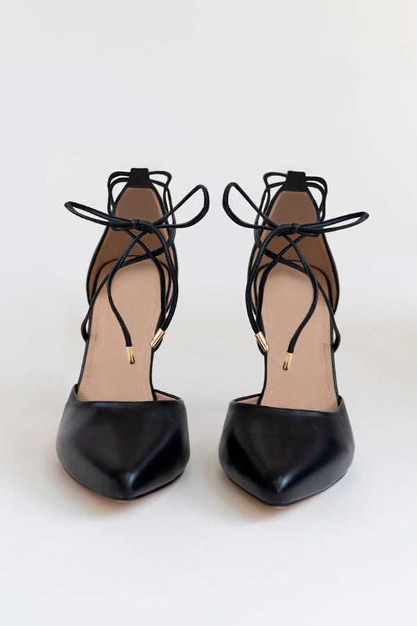 A pair of black leather high-heeled pumps with pointed toes and intricate lace-up ankle straps, shown against a plain light background.