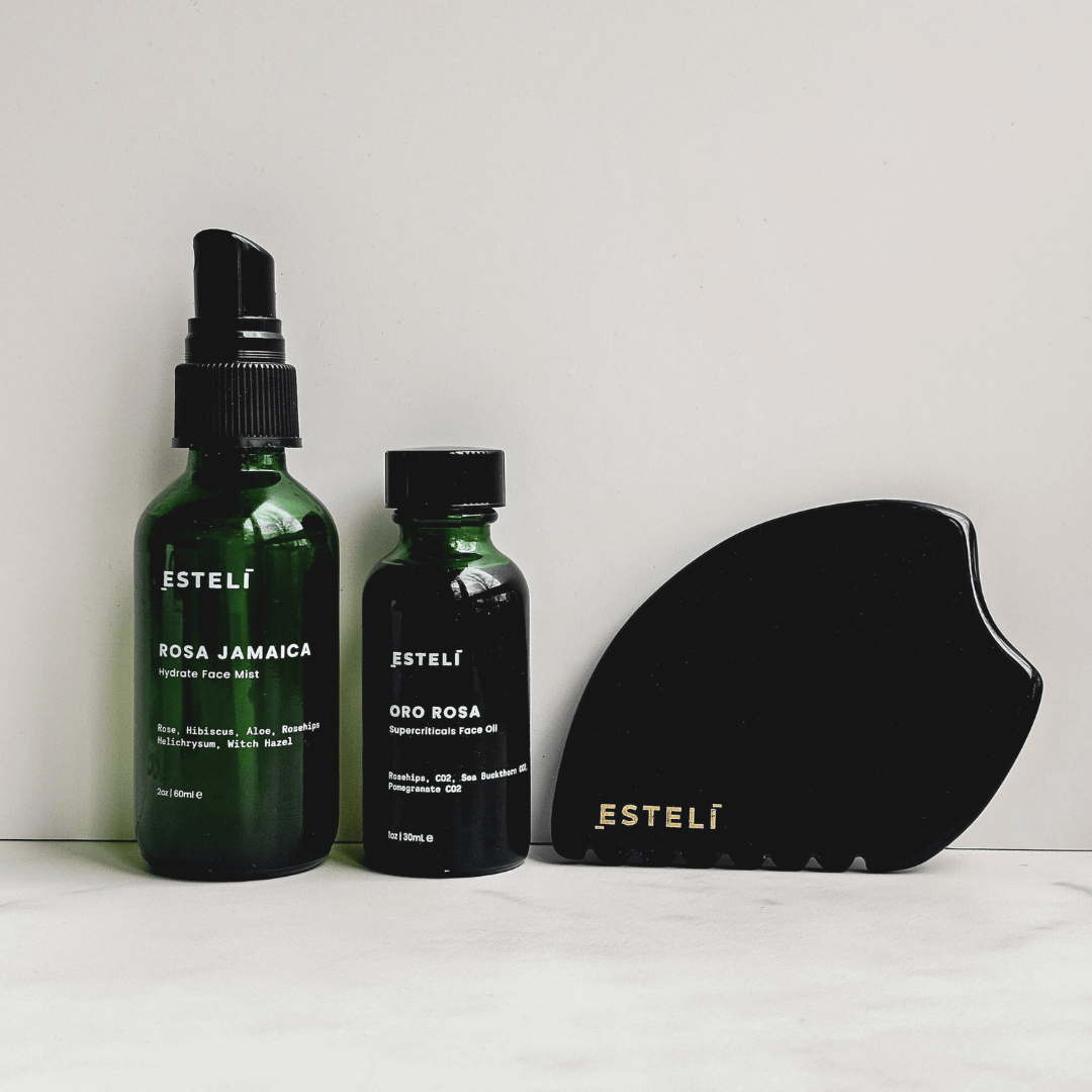 Two green Esteli bottles and a black Obsidian Gua Sha on a white background