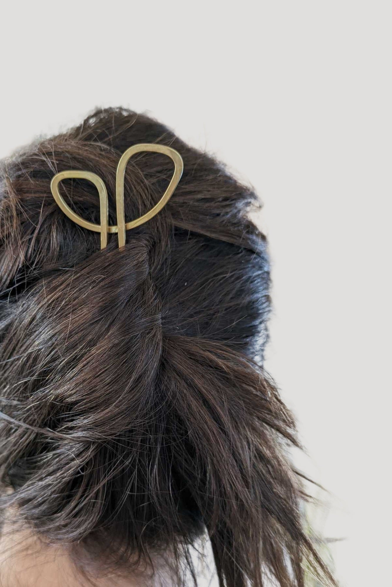 Gold hair clip in a person's braided hair against a light background