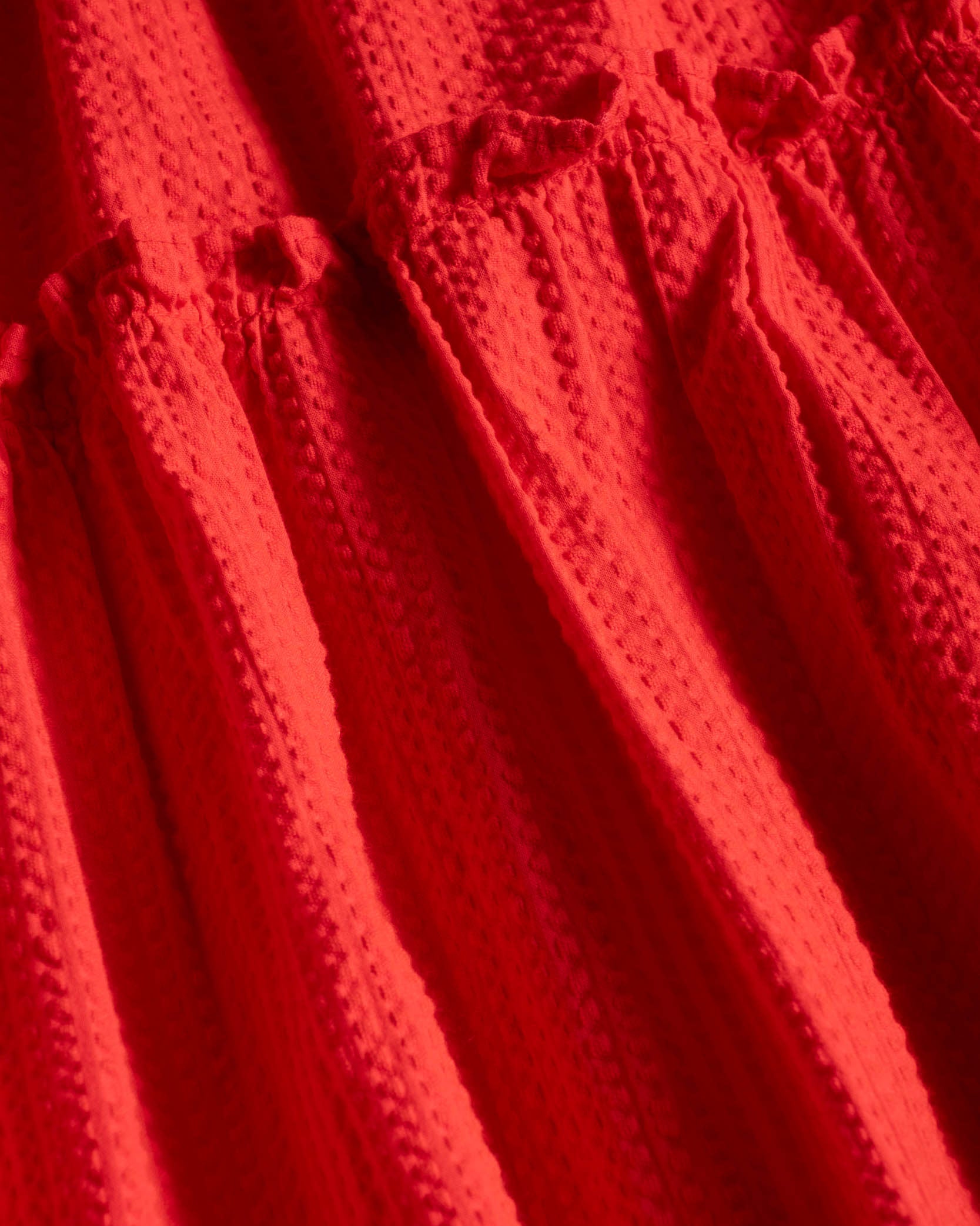 Close-up of a red textured fabric with a bow detail