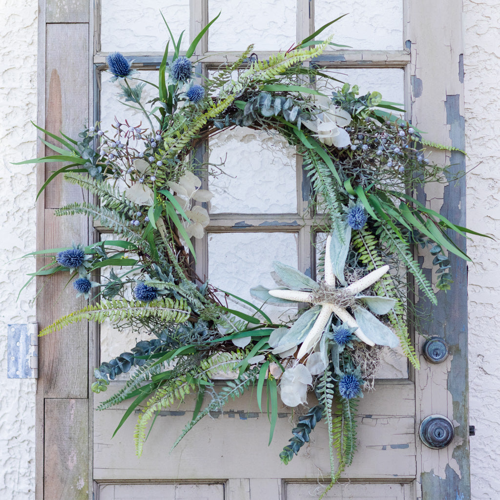 Decorative wreath with greenery and flowers on a wooden door