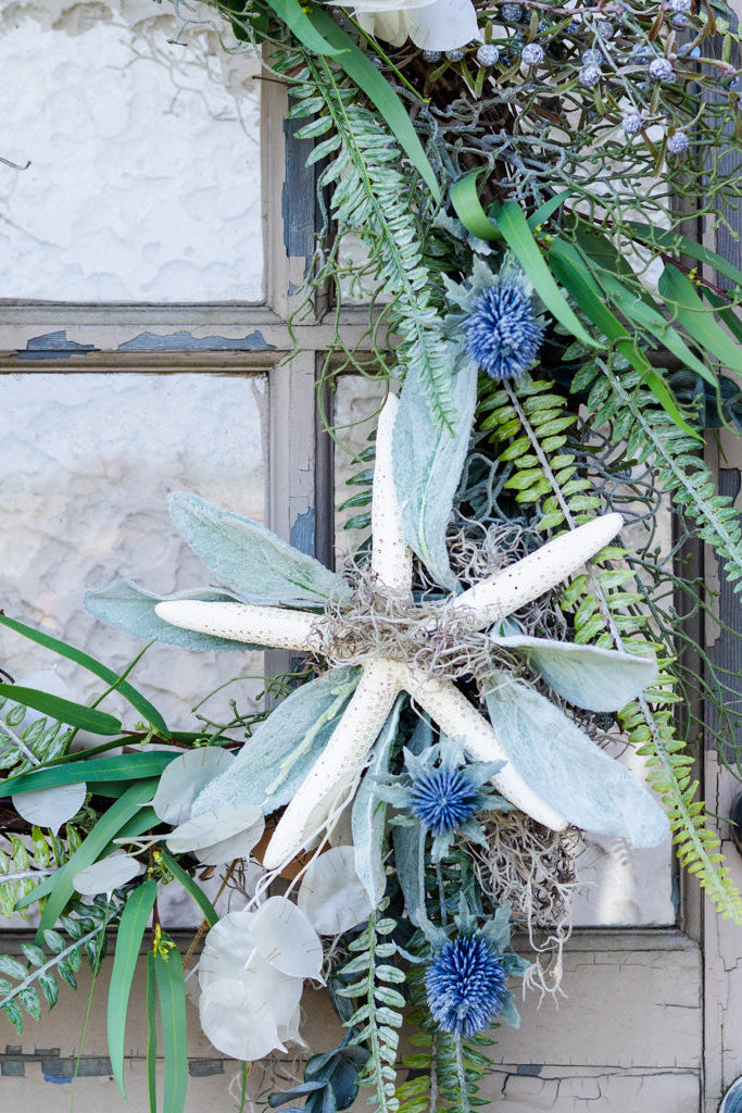 Decorative wreath with greenery and blue flowers on a door