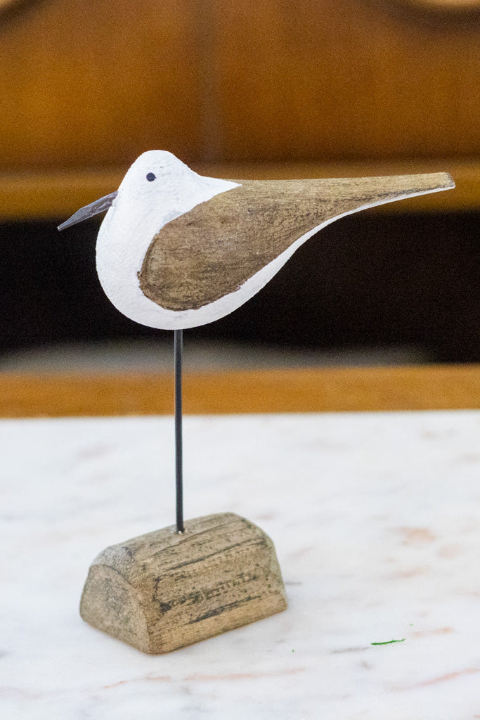 Wooden seagull figurine on a stand with a blurred background