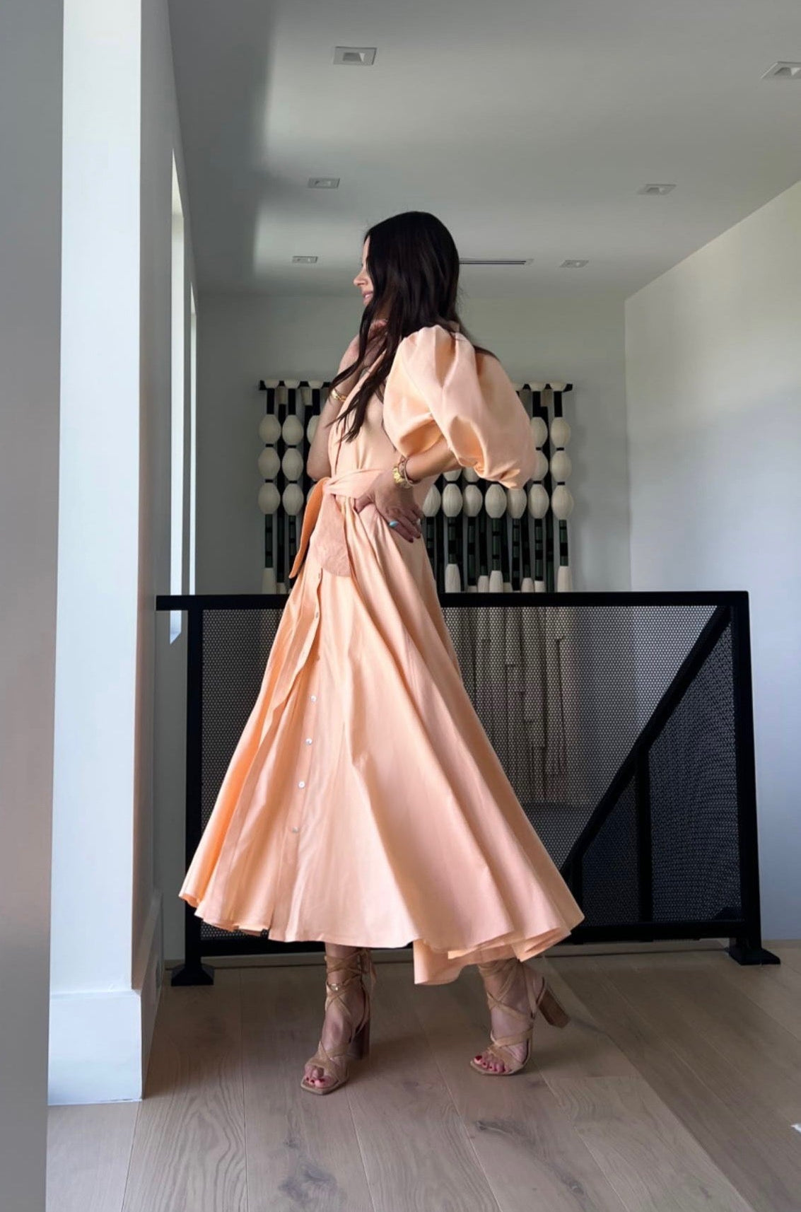 Woman in a peach dress standing in a modern interior setting