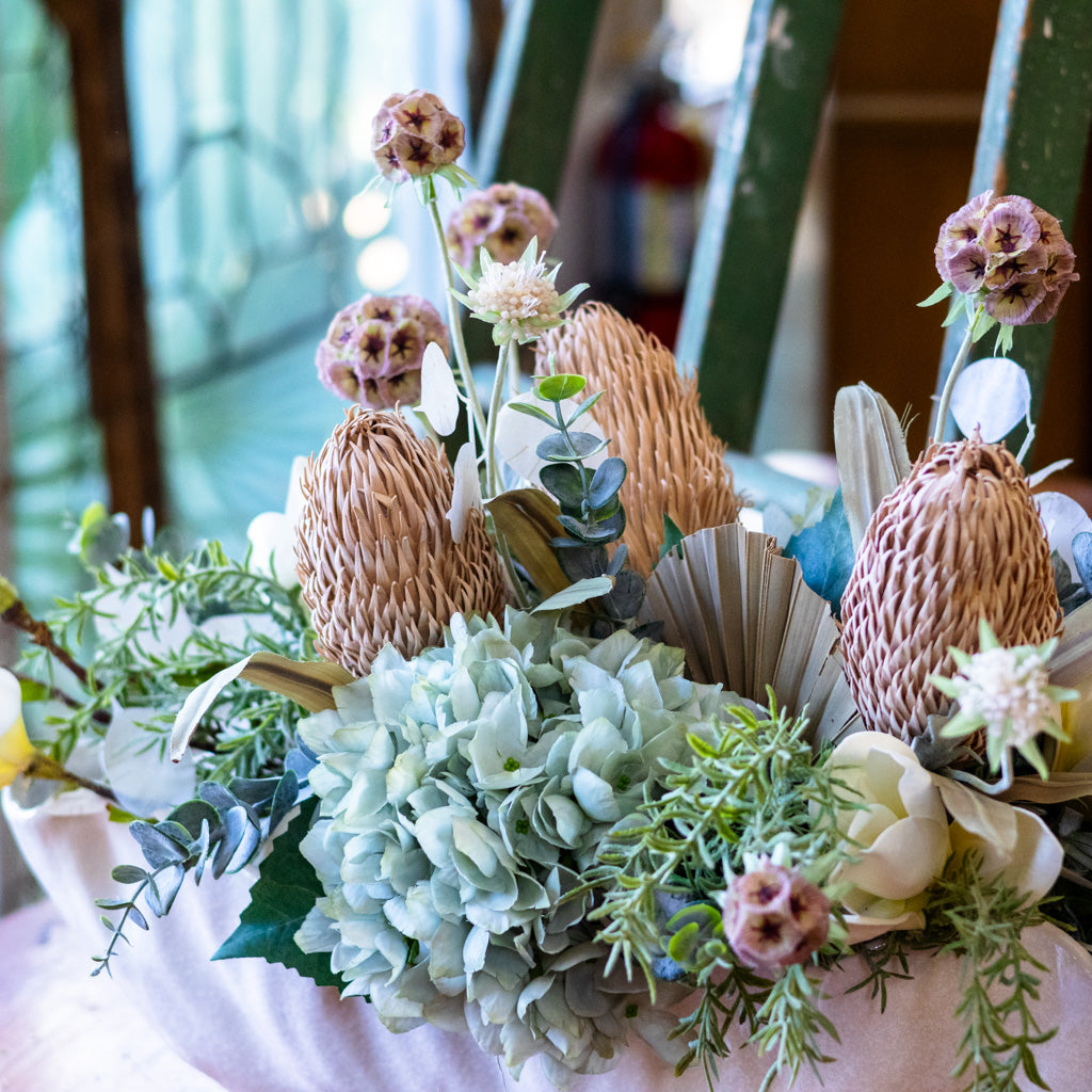 Decorative floral arrangement with dried elements on a table.