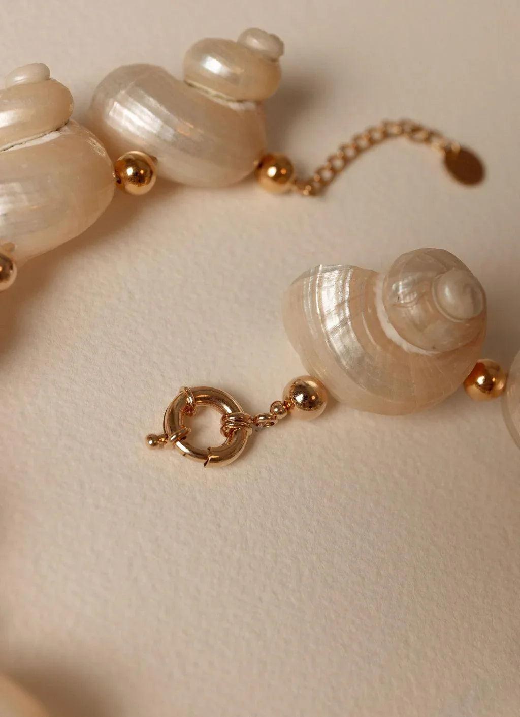 Sea shell bracelet with gold accents on a neutral background