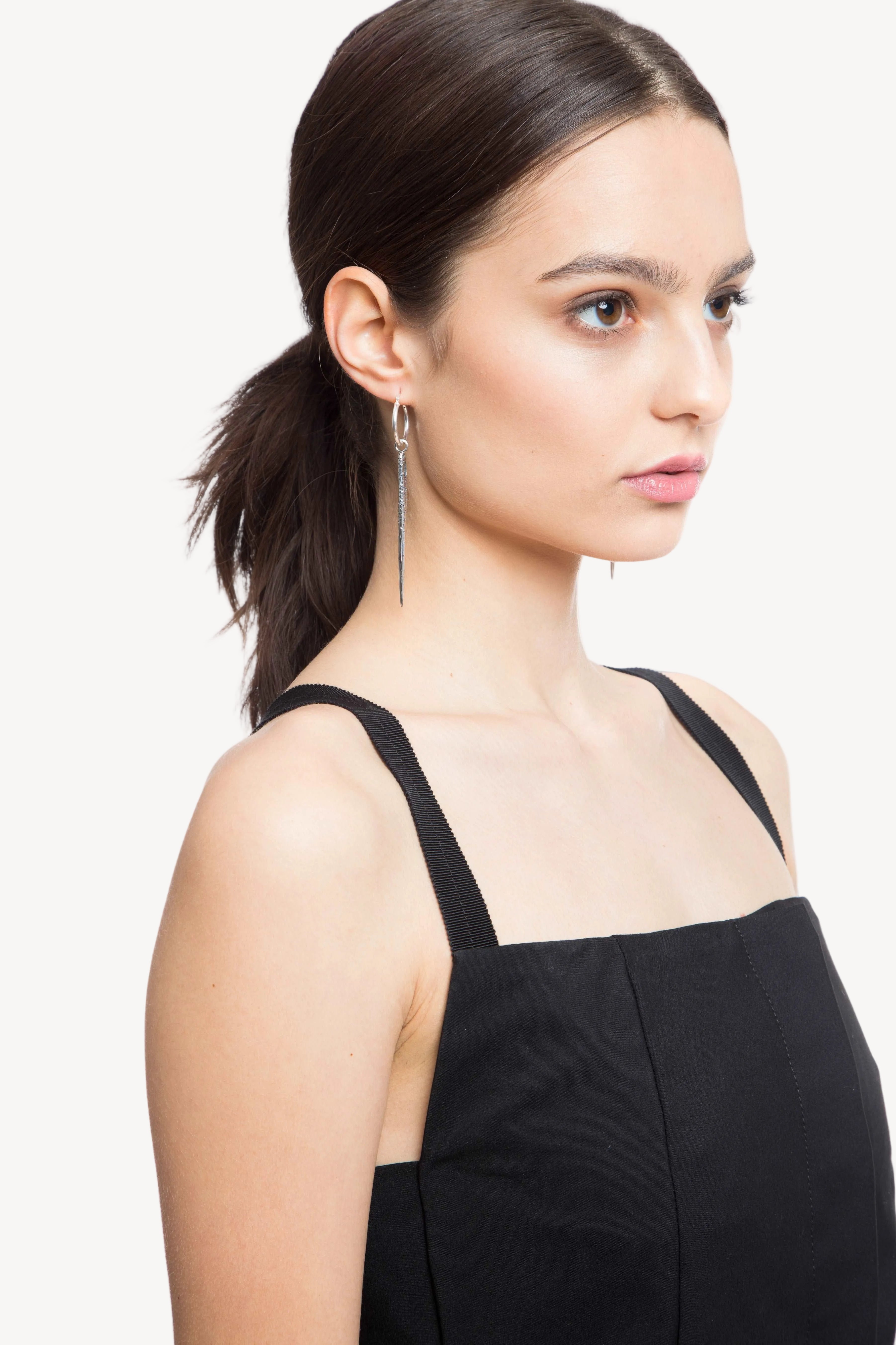 Woman wearing a black dress with thin straps on a white background