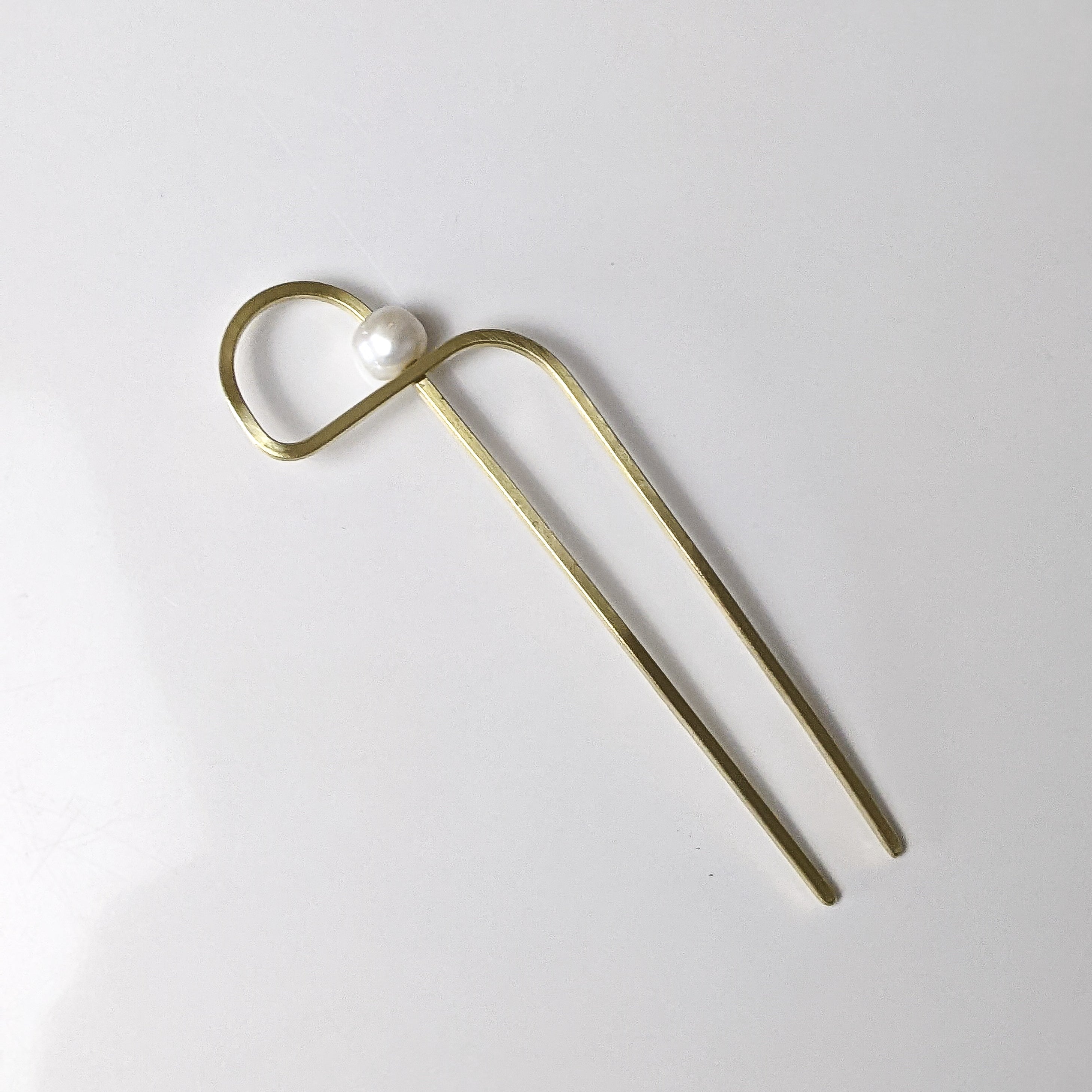 Gold hairpin with a pearl on a white background