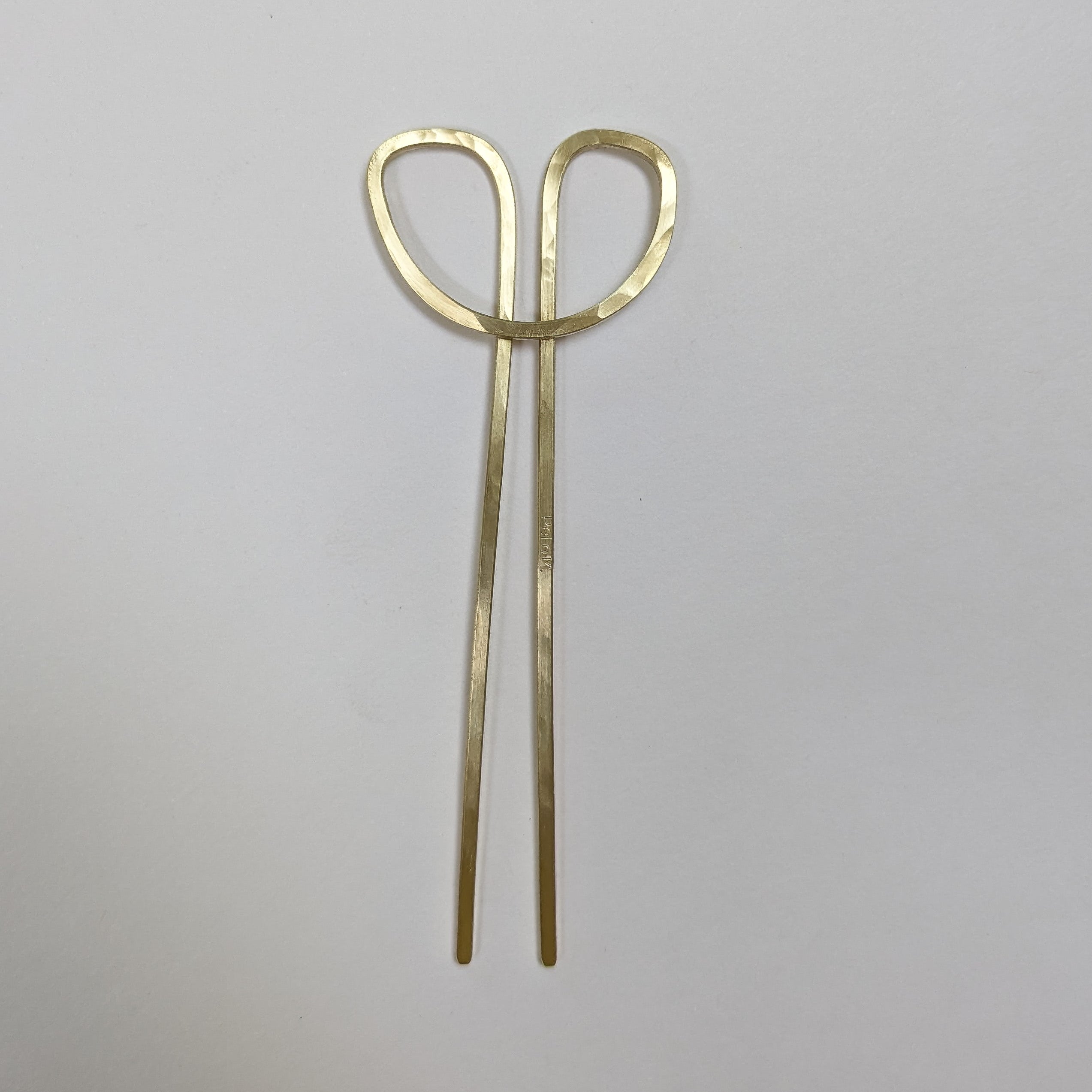 Pair of gold hair styling clips on a light gray background