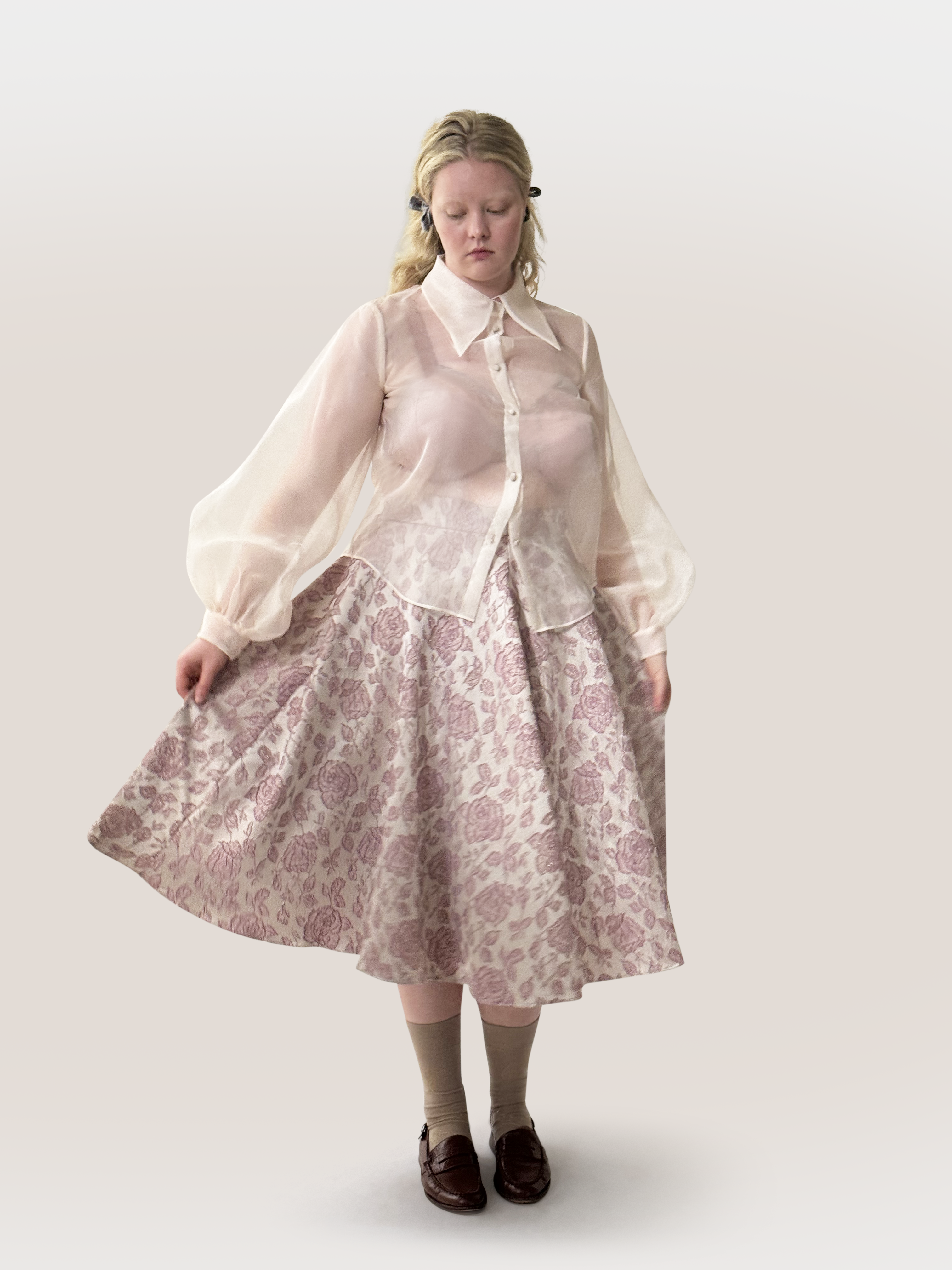 Woman wearing a floral skirt and sheer blouse on a white background