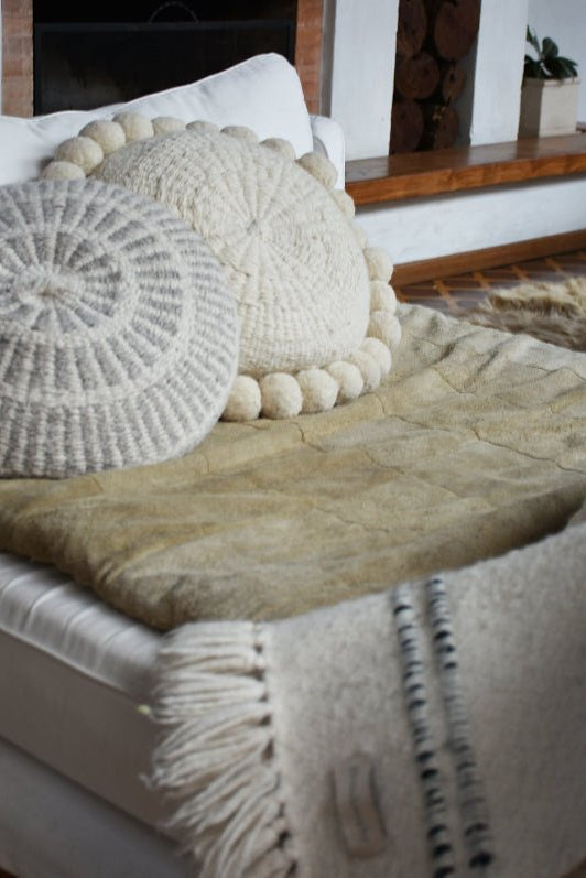 Decorative pillows and blanket on a bed with a fireplace in the background