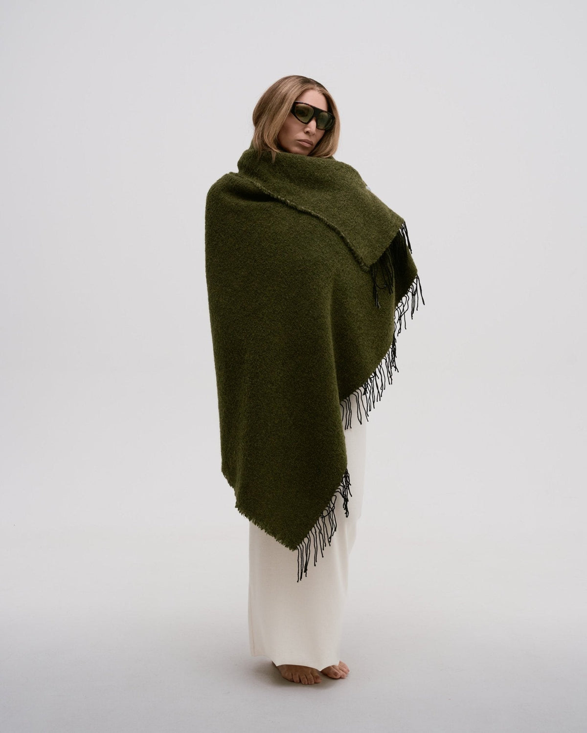 Person wearing a green scarf with fringe on a white background