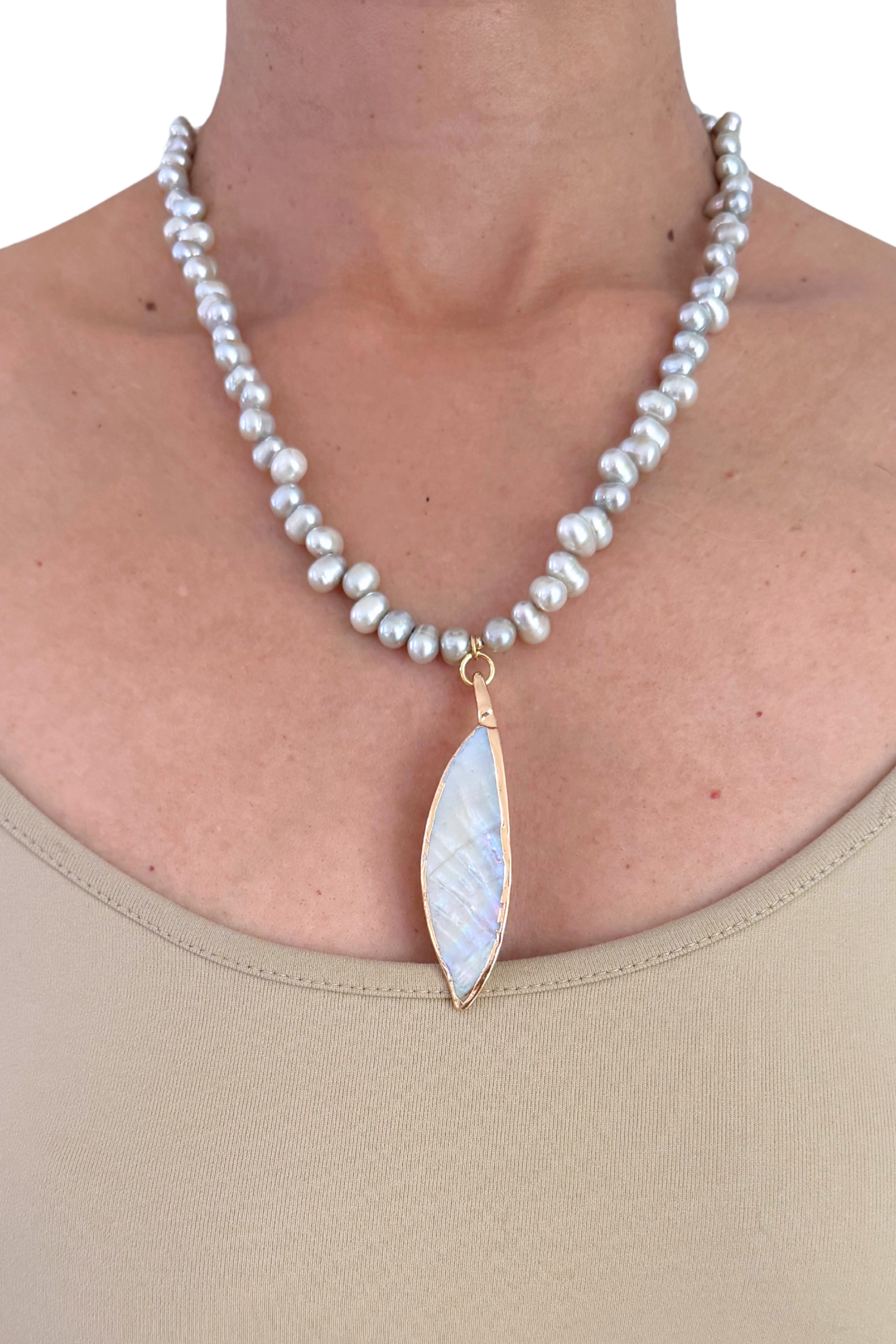 Pearl necklace with a leaf-shaped pendant worn by a person