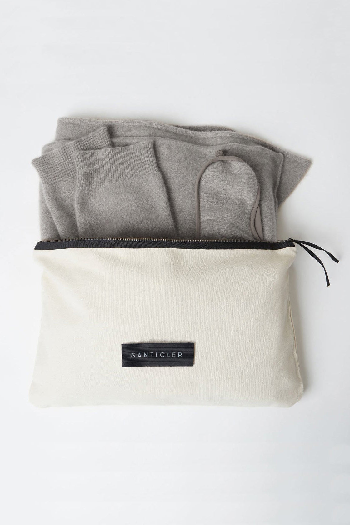 Folded gray cashmere travel set inside a beige travel pouch with 'Santicler' branding on a white background