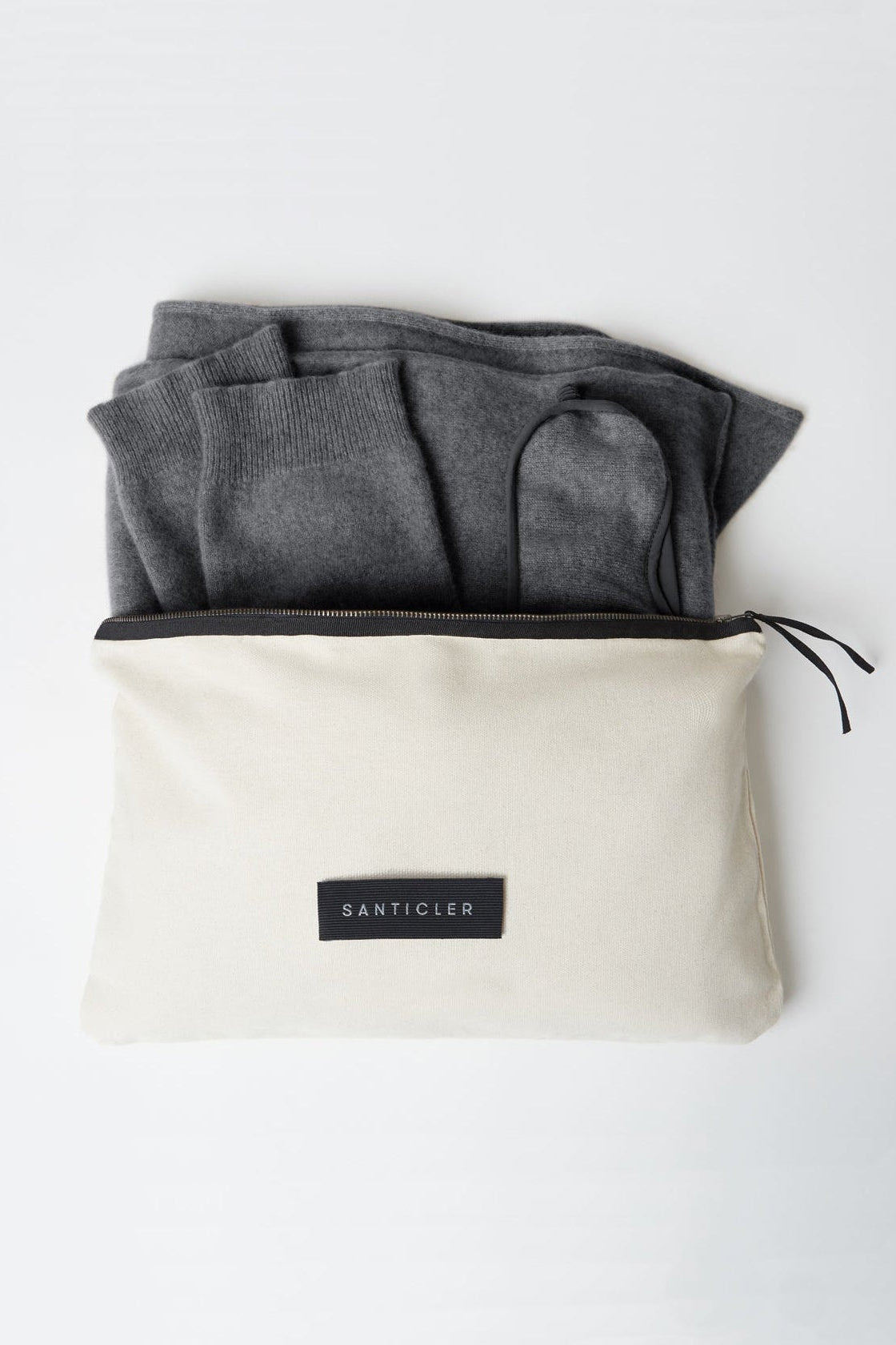 Beige travel pouch with gray folded clothes inside on a white background, featuring the brand 'Banticler'.