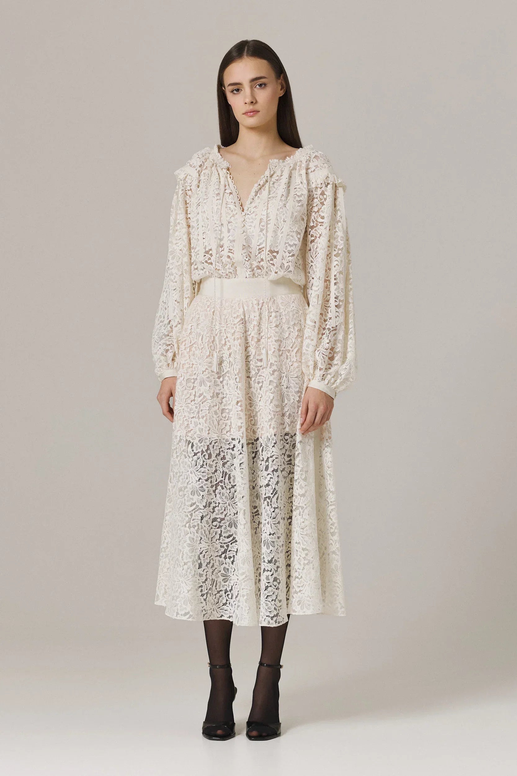 Woman wearing a white lace dress on a plain background