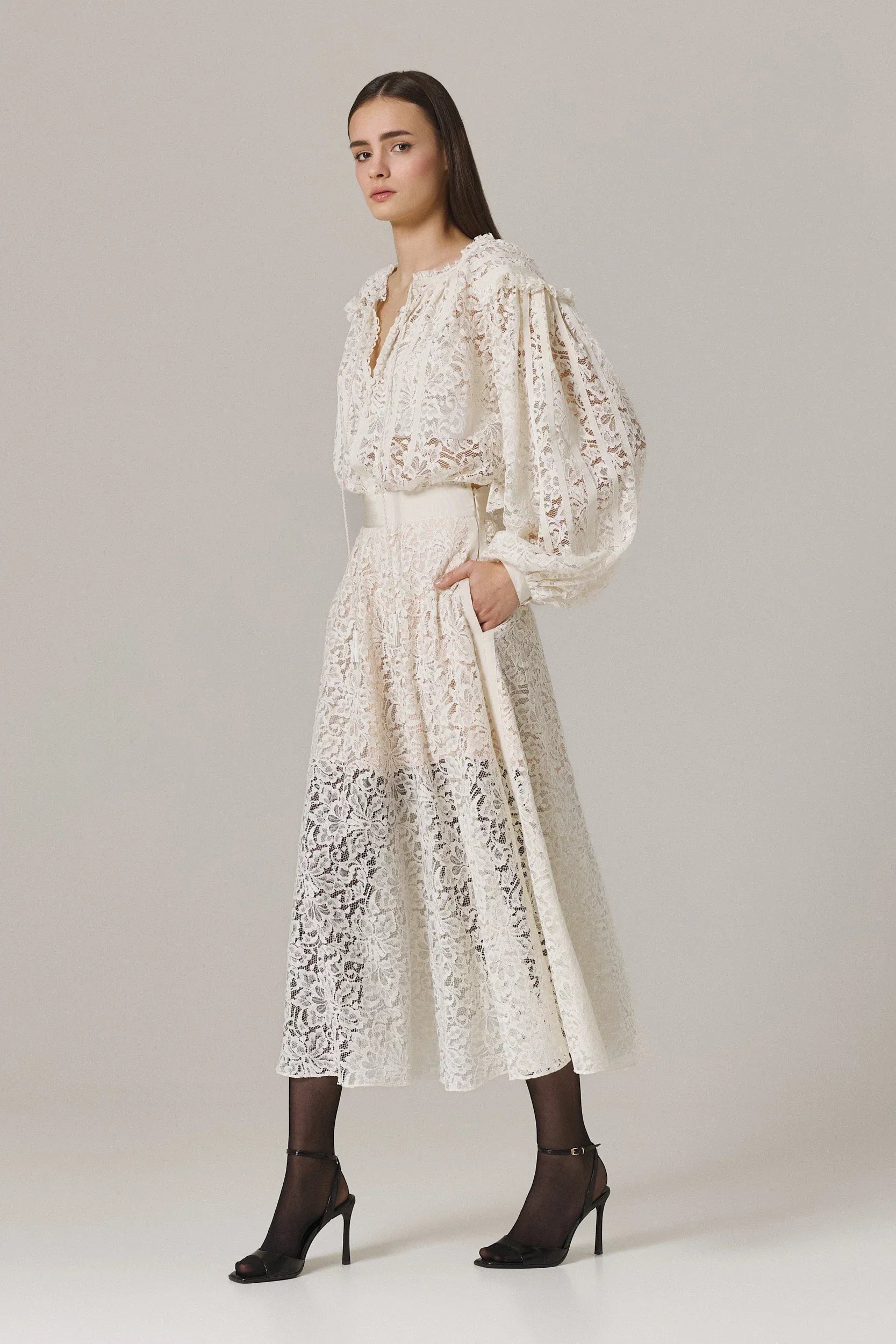 Woman wearing a white lace dress on a plain background