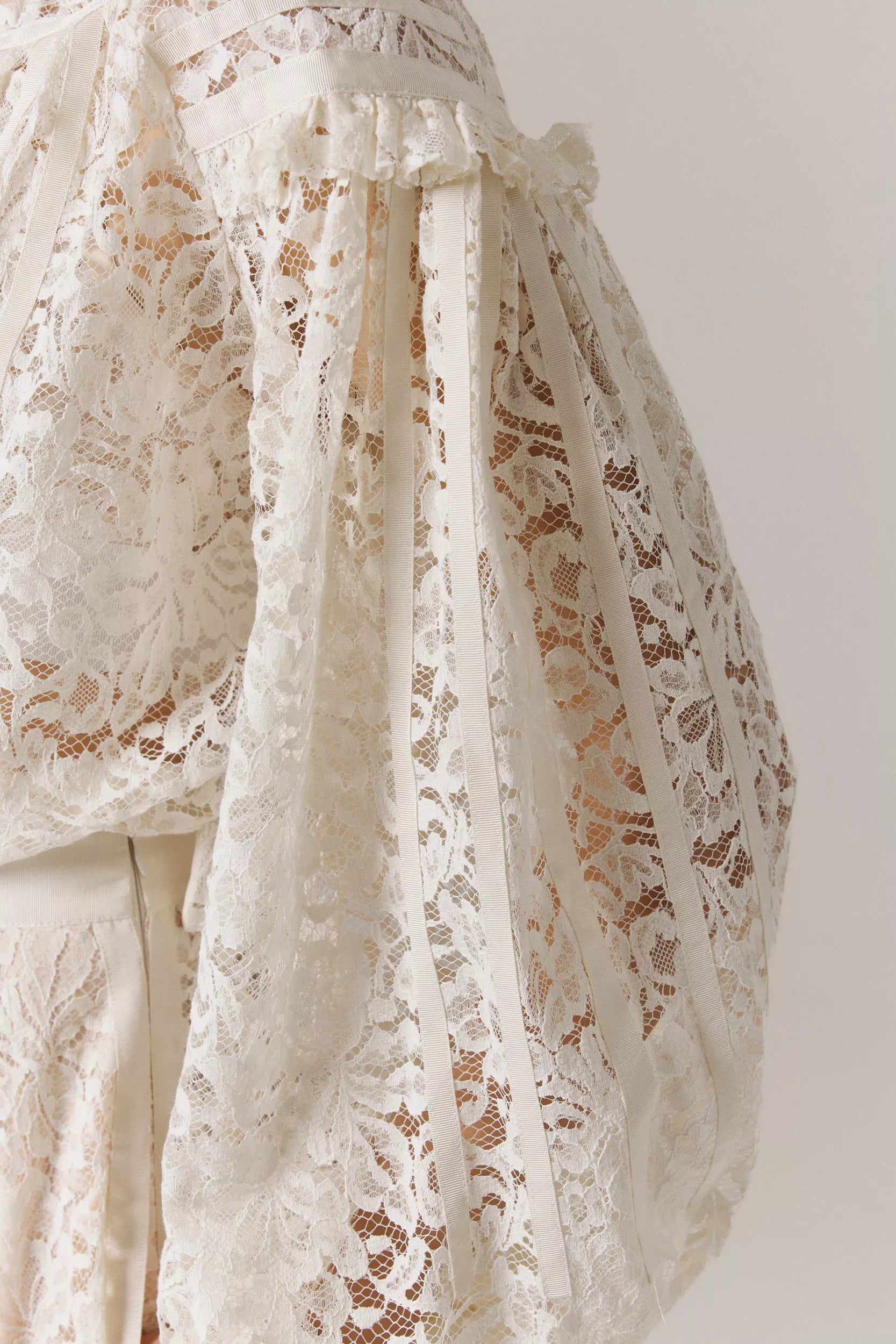 Close-up of a lace garment sleeve with a neutral background
